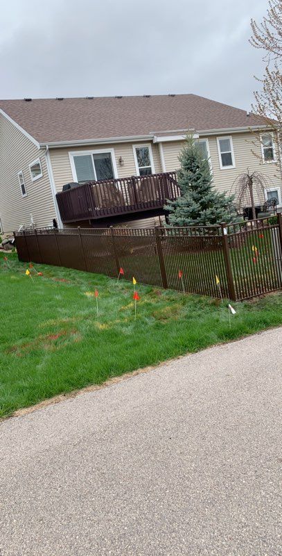 A house with a deck and a fence in front of it.