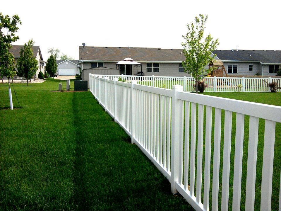 A white fence surrounds a lush green yard