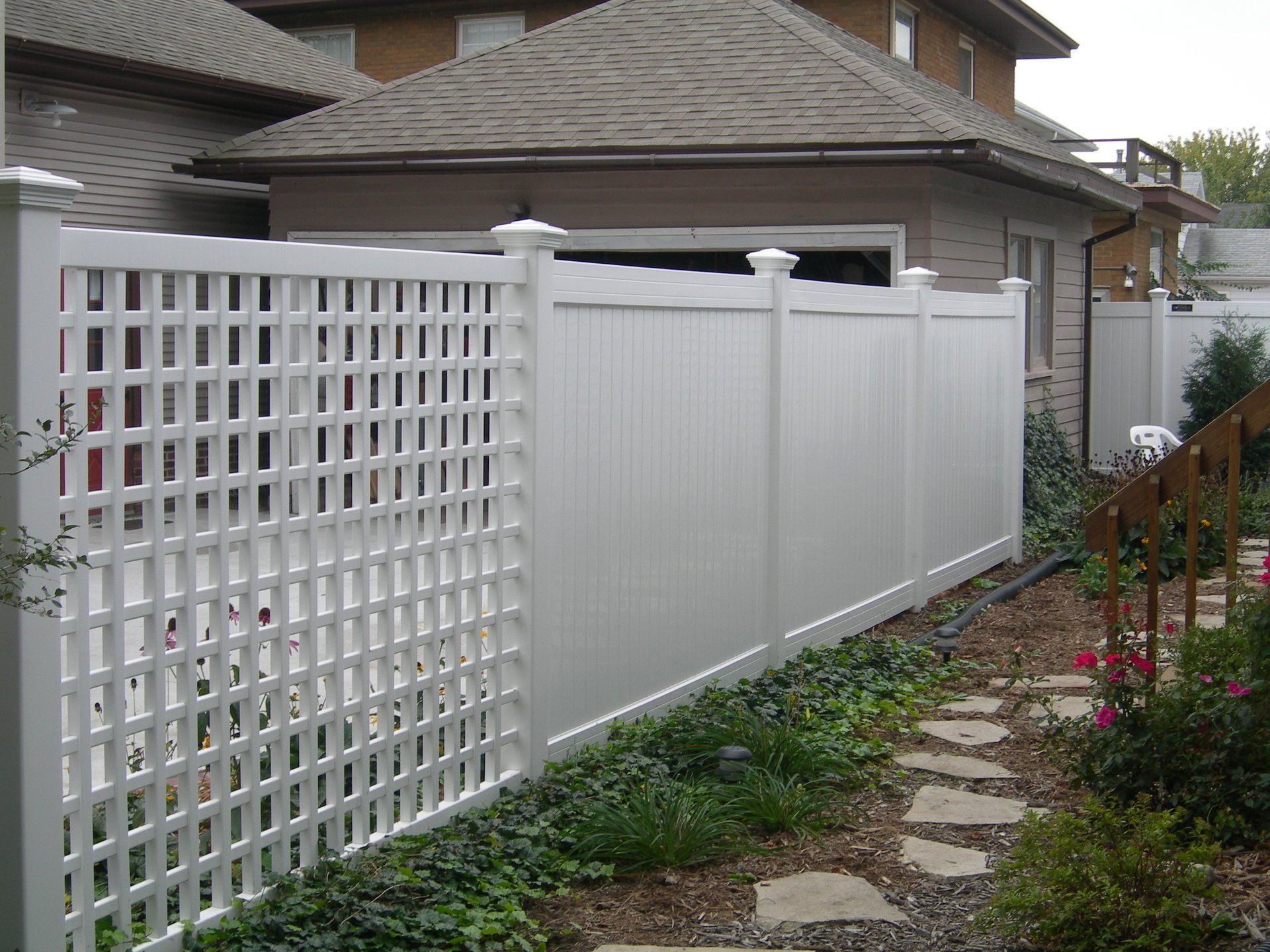 A white fence with a lattice design is in front of a house