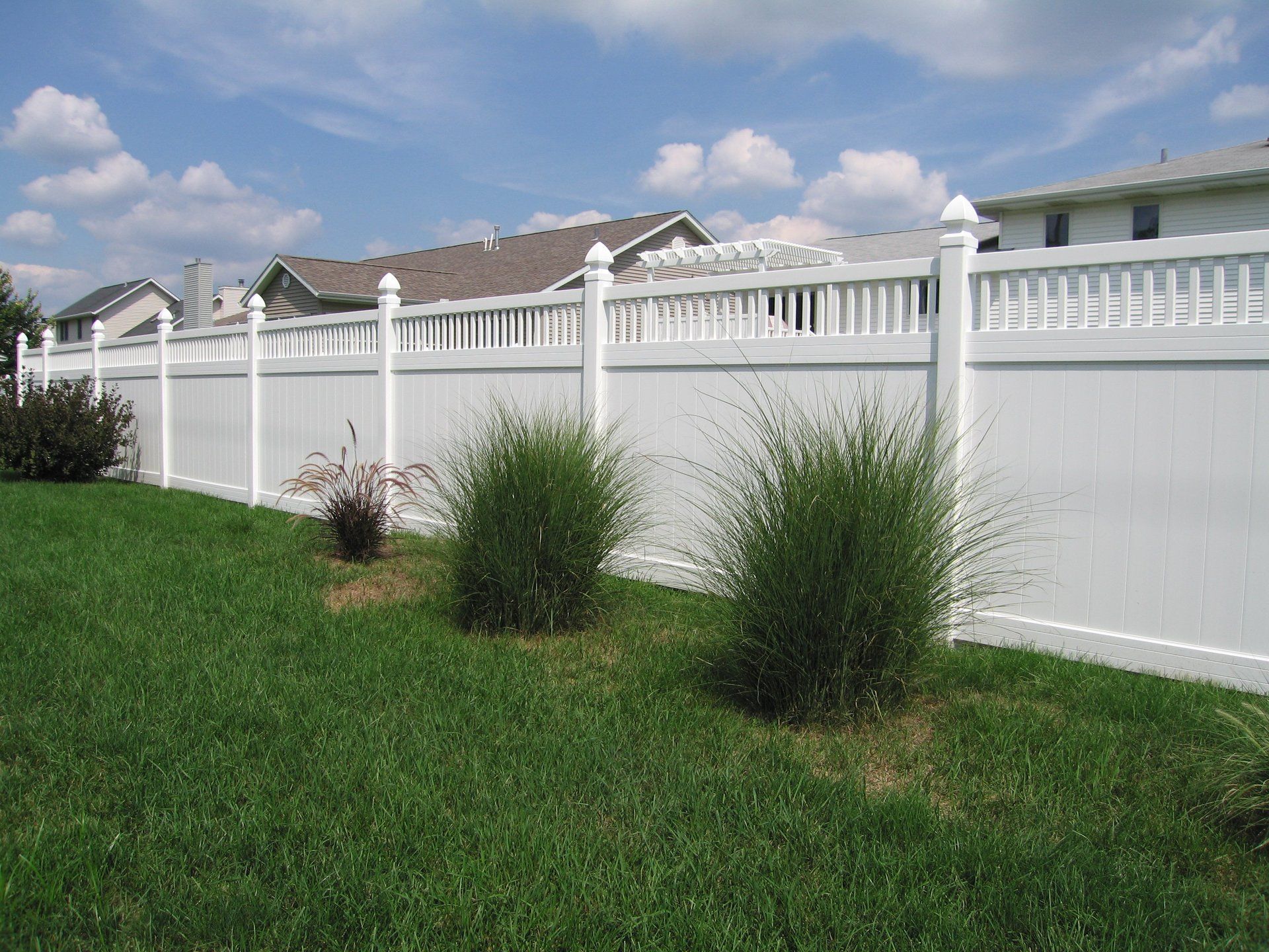 A white fence surrounds a lush green yard.