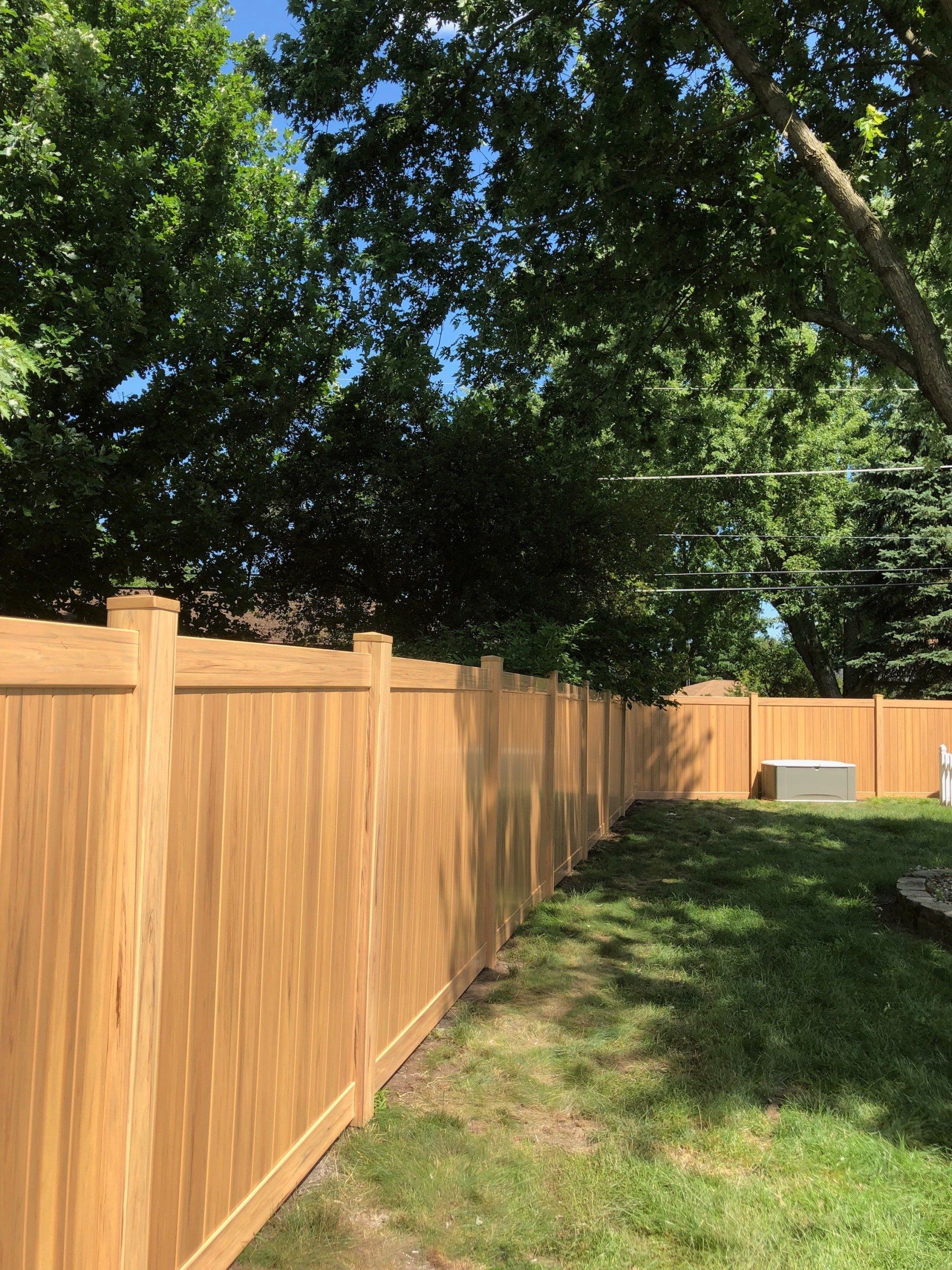 A wooden fence surrounds a lush green yard.