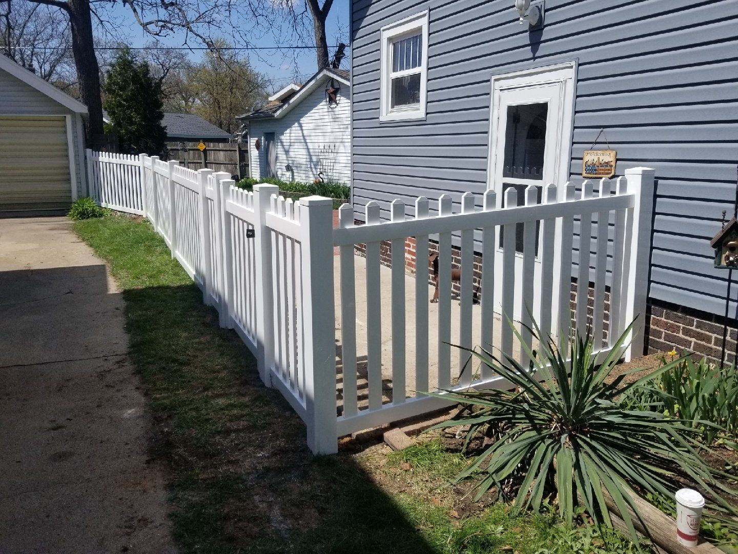 A white picket fence is in front of a blue house.