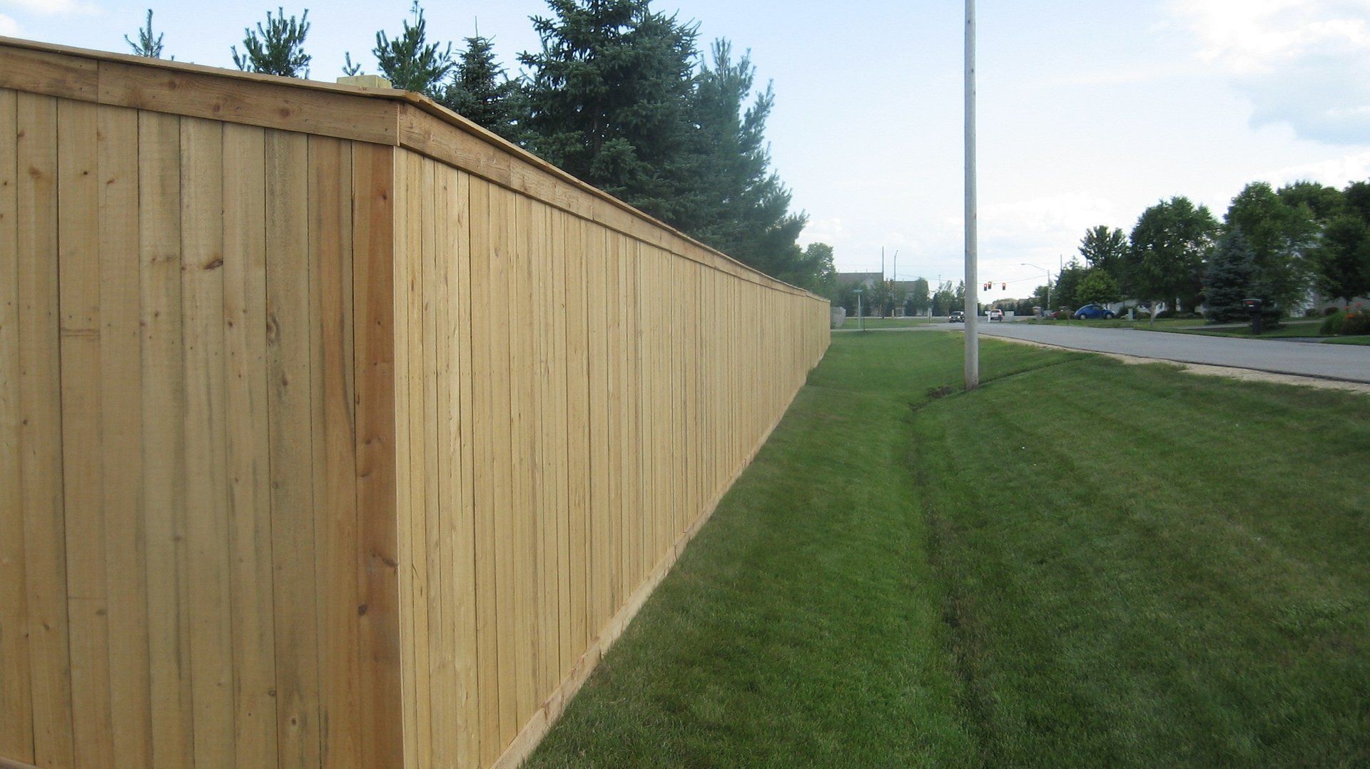 A long wooden fence surrounds a lush green field.