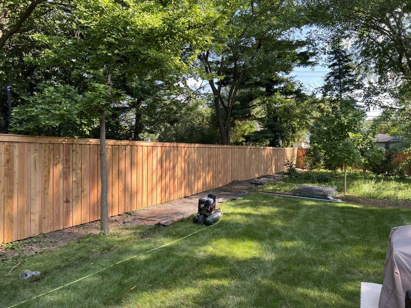 A wooden fence is being built in a backyard.