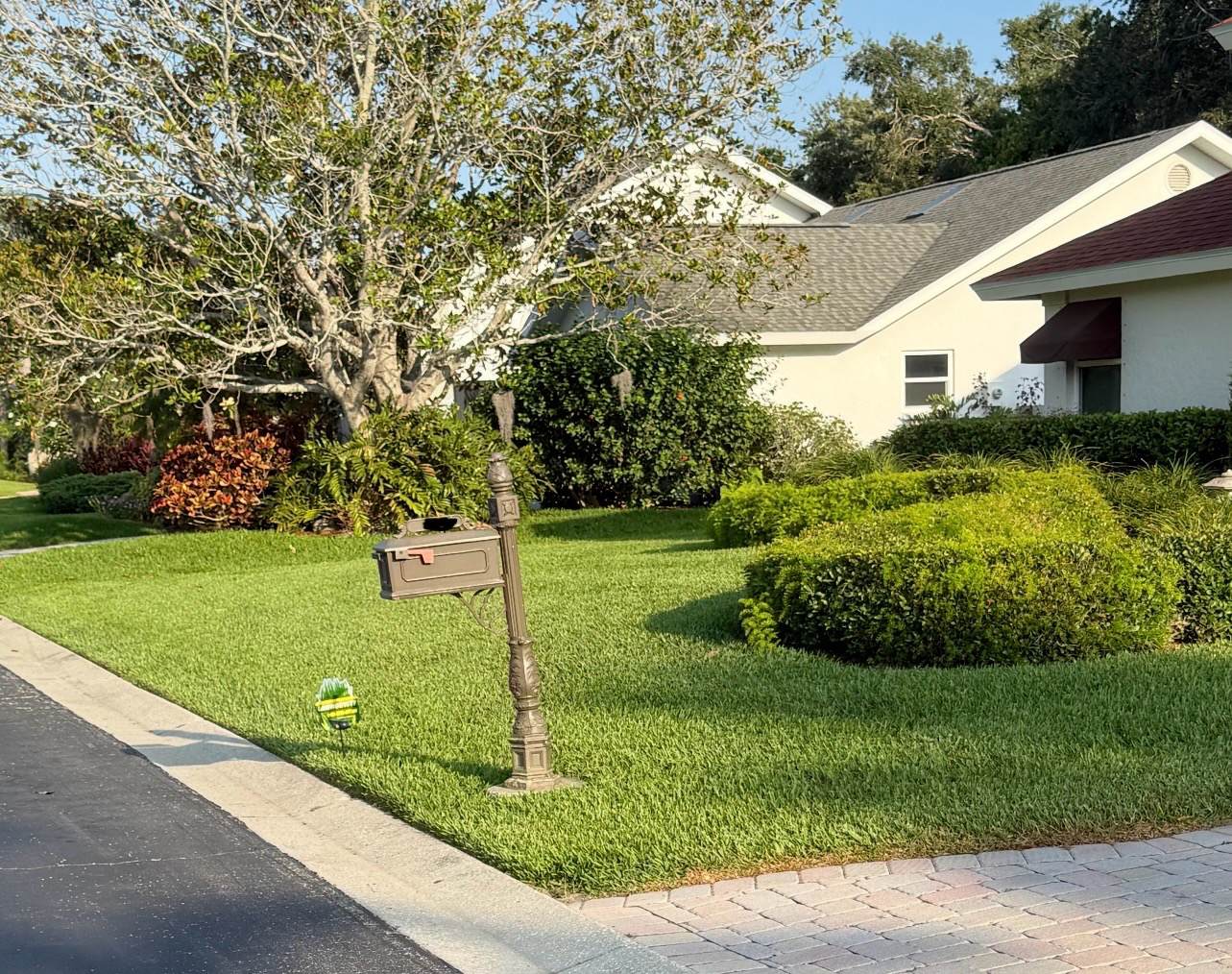 A mailbox is in the middle of a lush green lawn in front of a house.