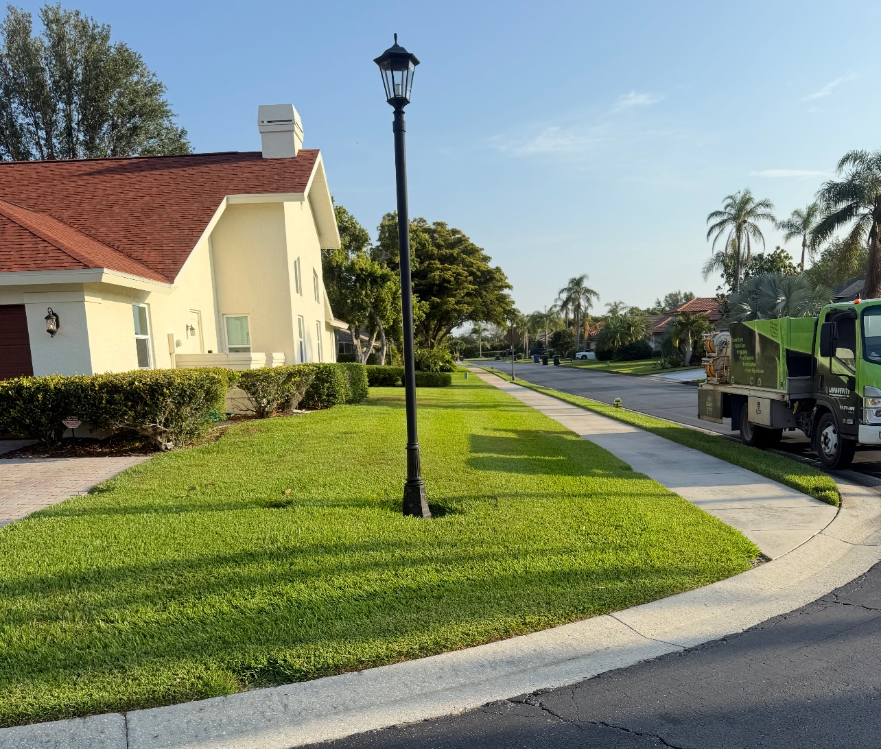 A green truck is parked on the side of the road in front of a house