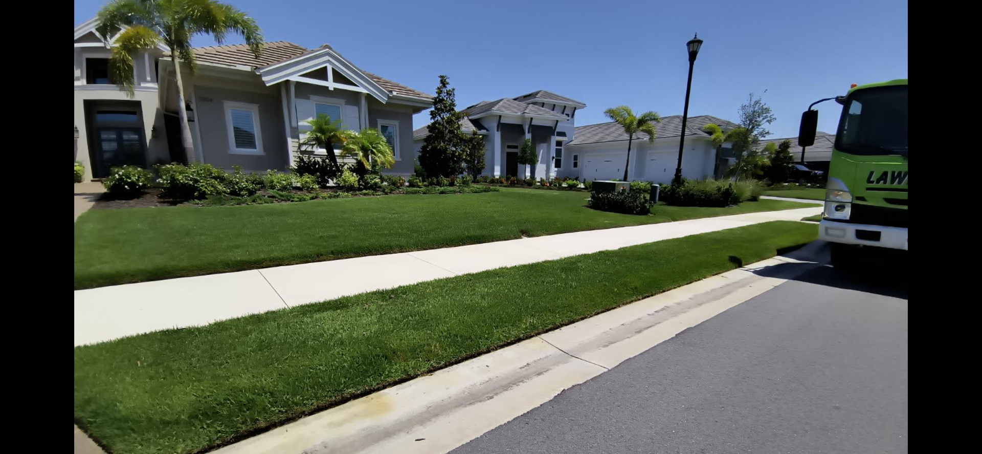 A green truck is parked in front of a house in a residential neighborhood.