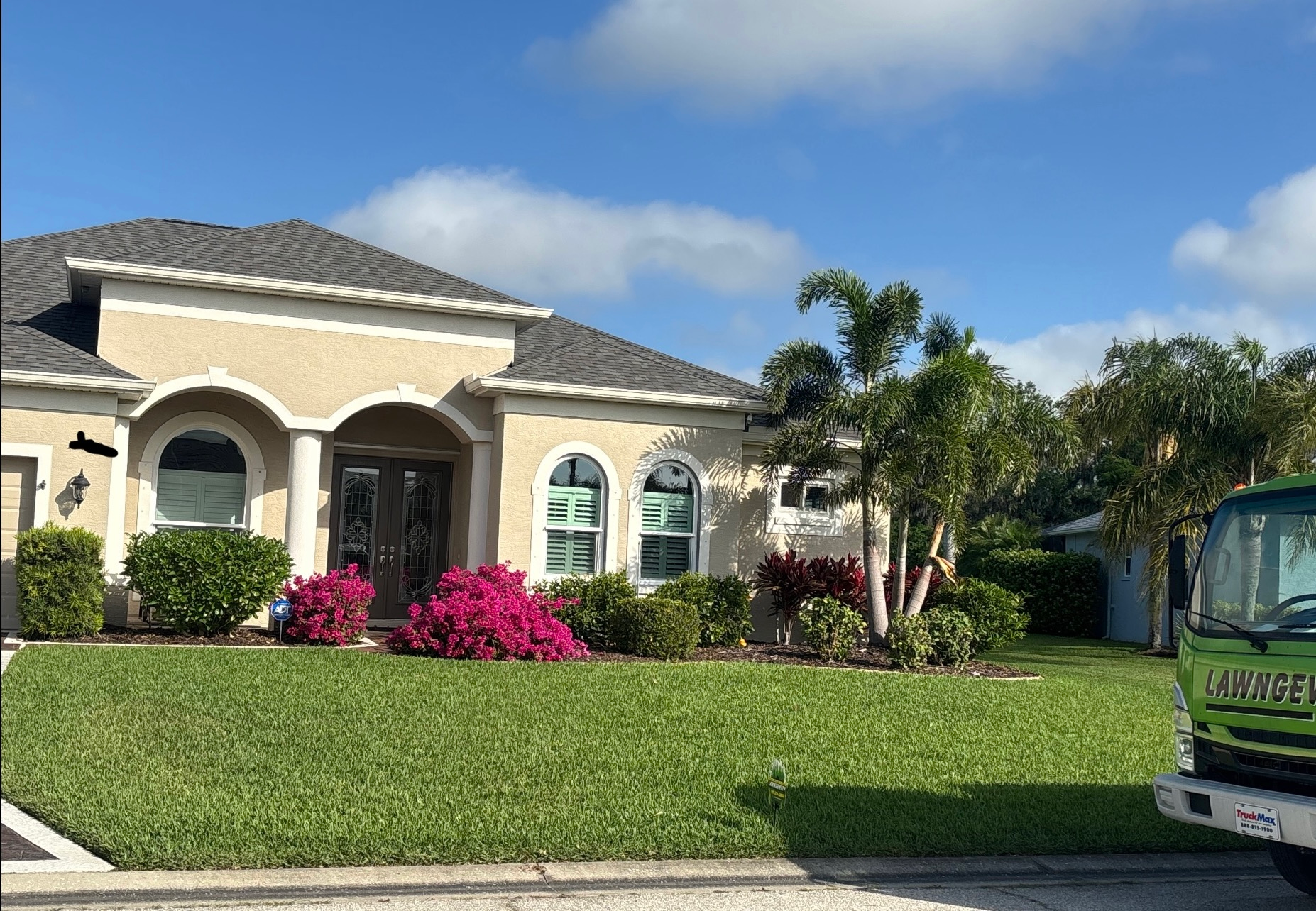 A large house with a green truck parked in front of it.