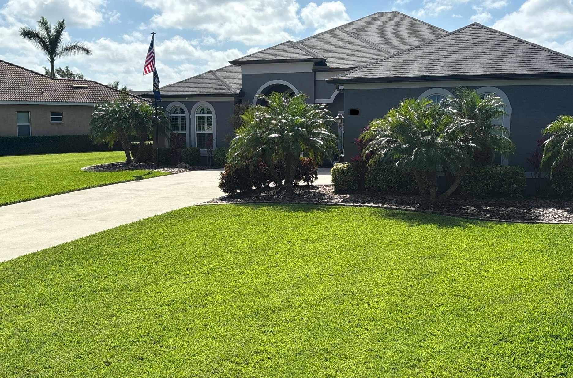 A large house with a lush green lawn and a driveway leading to it.
