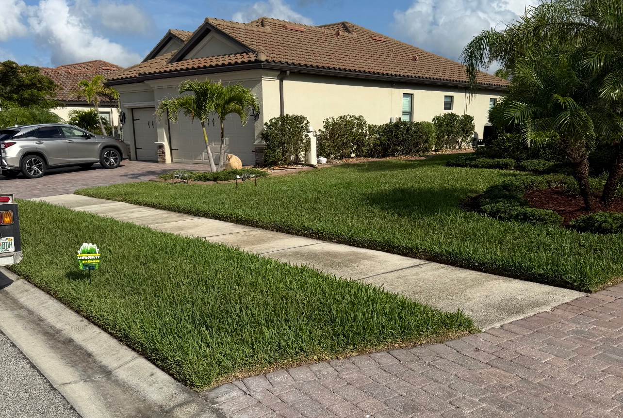 A house with a lush green lawn and a car parked in front of it.