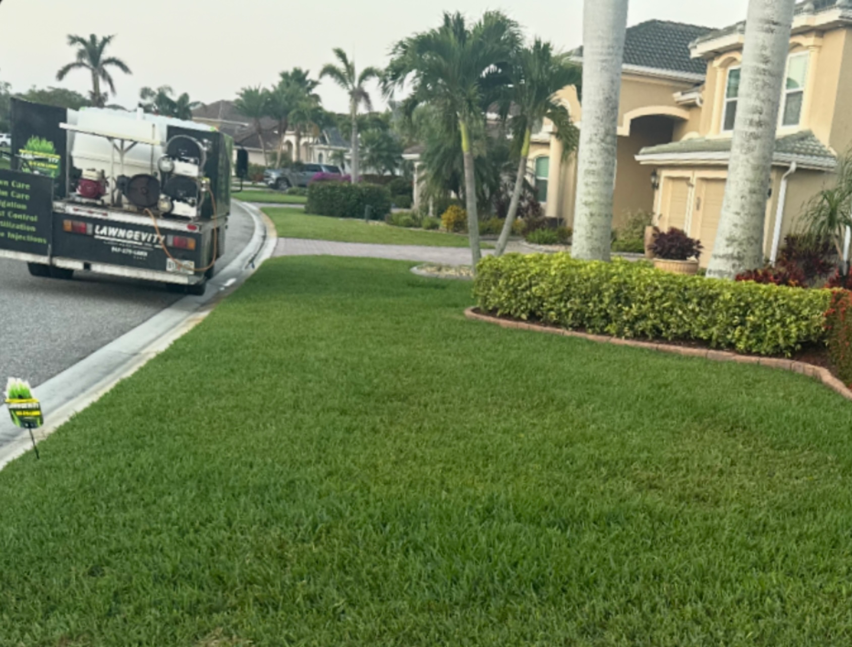 A truck is parked on the side of the road next to a lush green lawn.