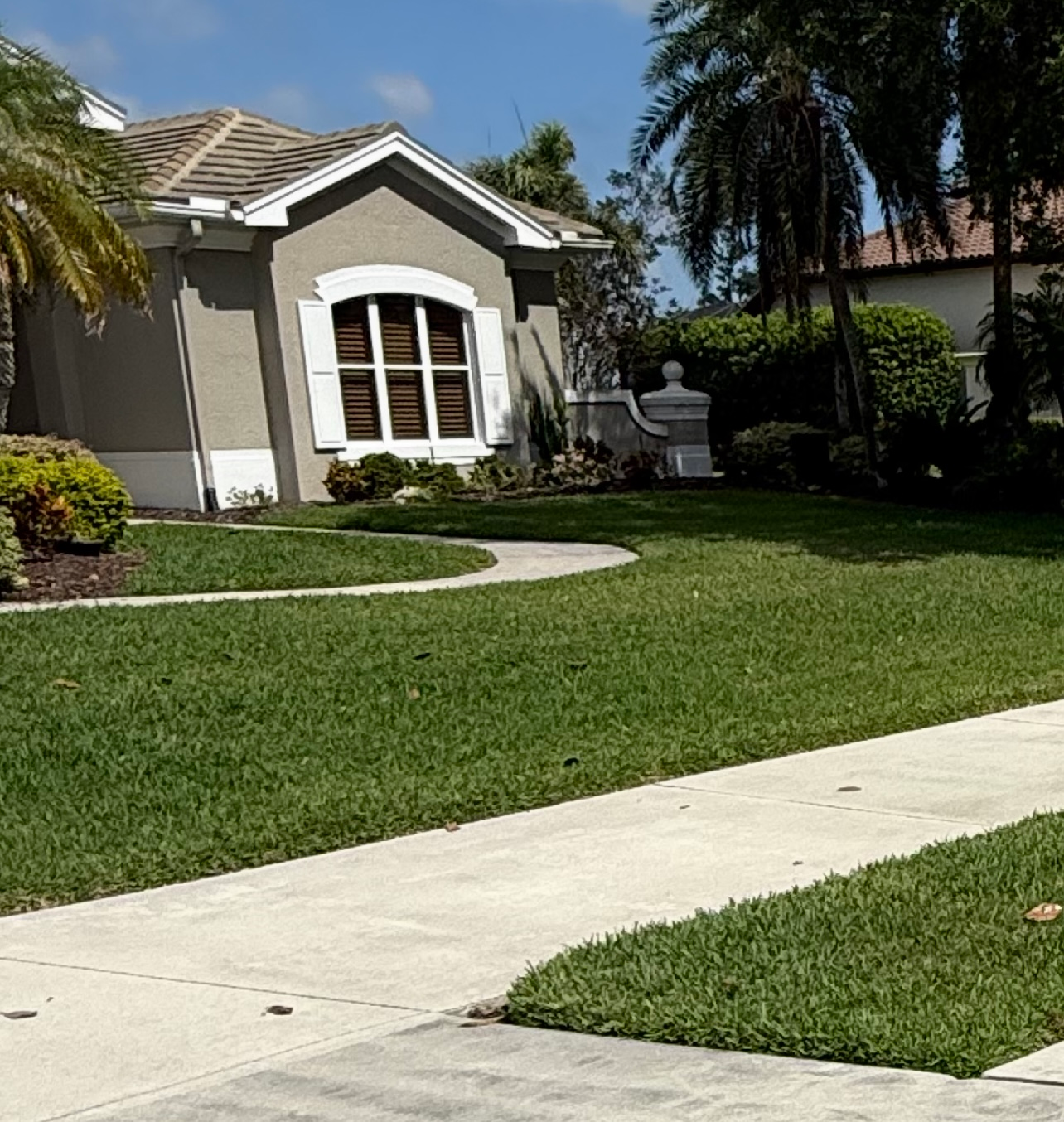 A house with a lush green lawn and a sidewalk in front of it