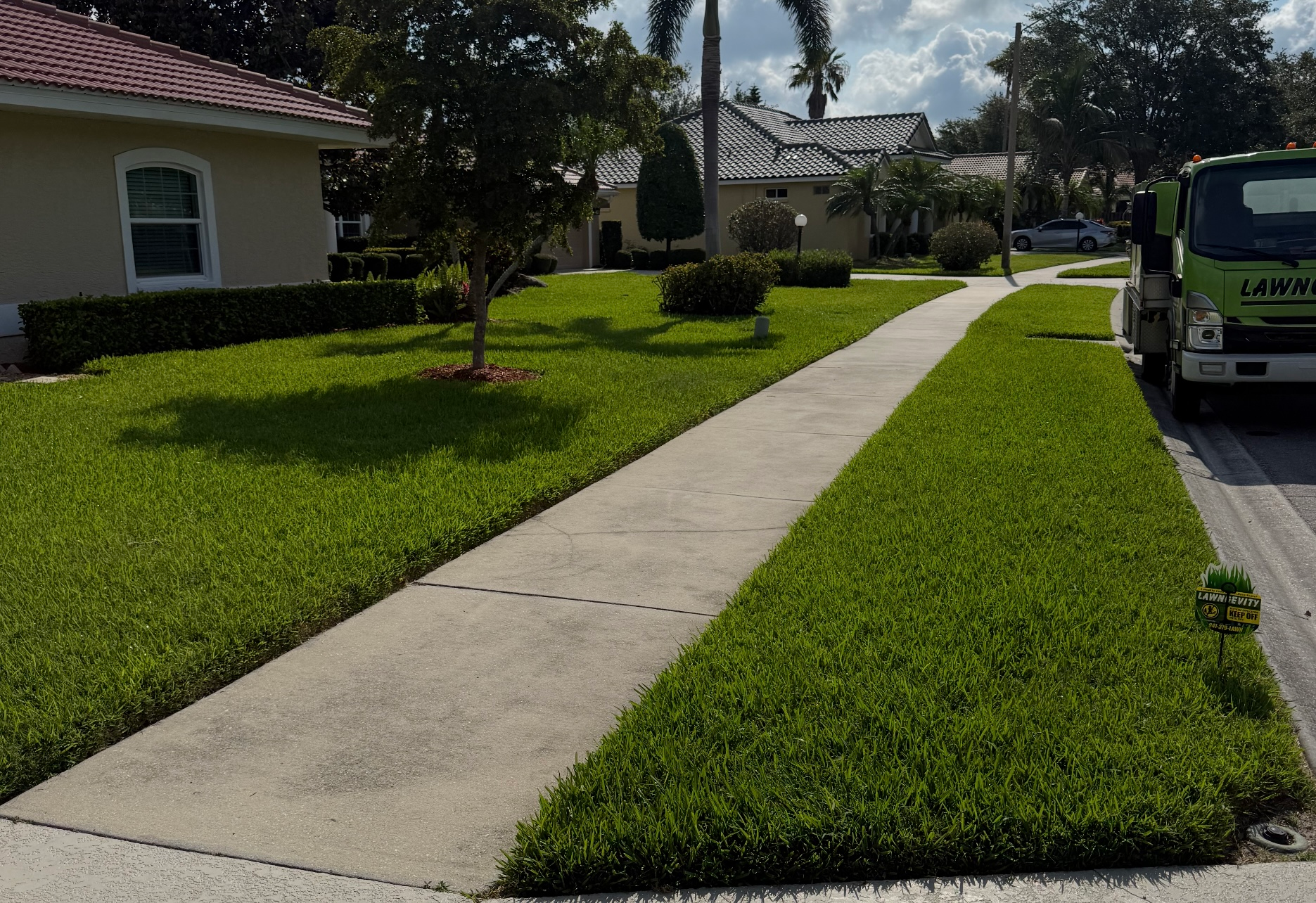 A green truck is parked on the side of the road in front of a house.