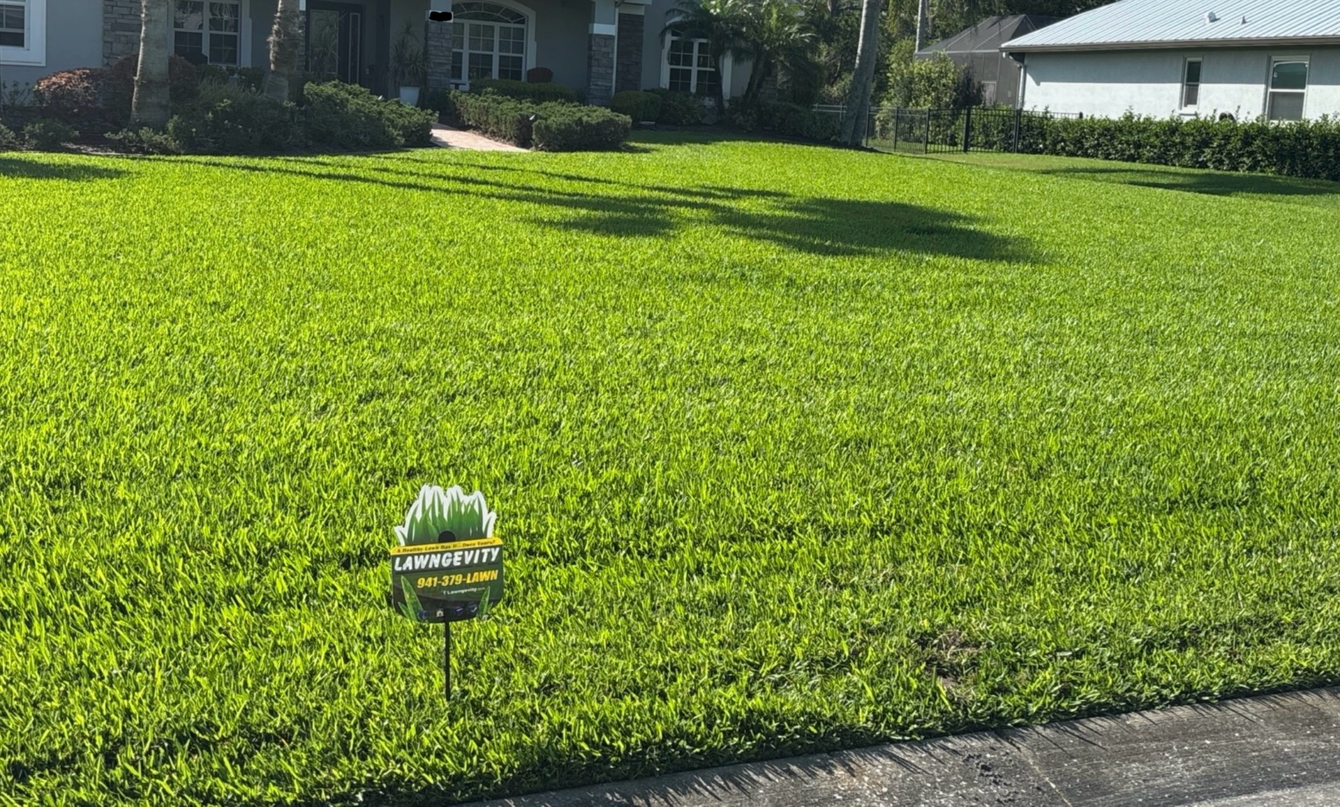 A lush green lawn with a sign in front of a house.