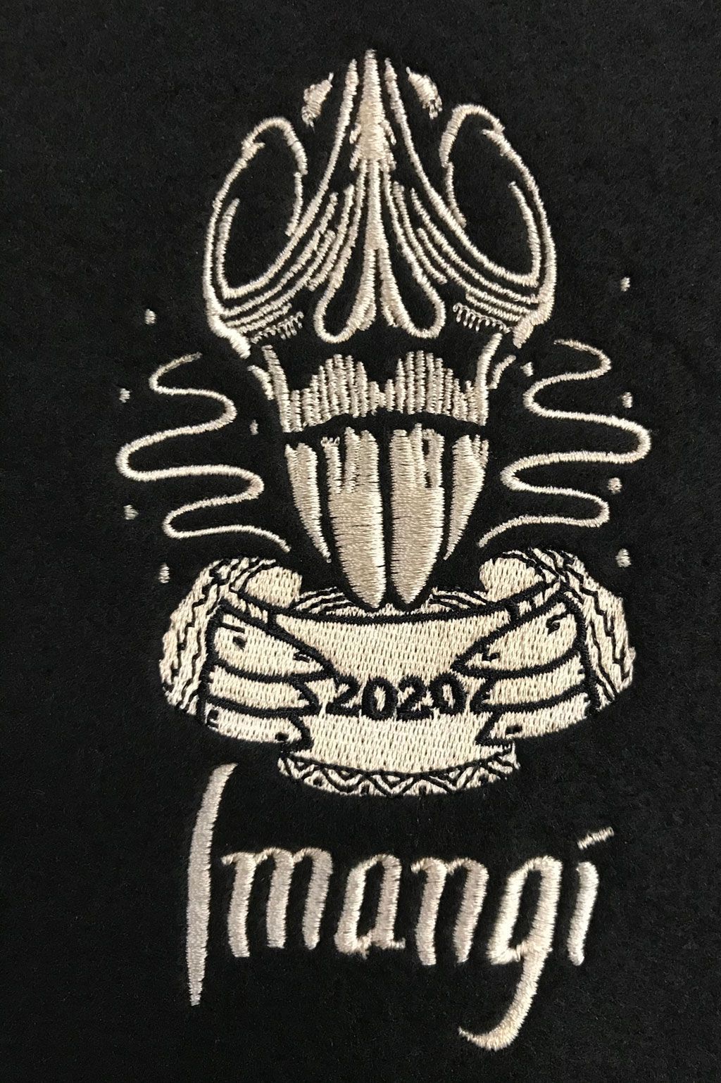 An embroidered logo featuring a stylized skull above skeletal hands holding a bowl labeled 