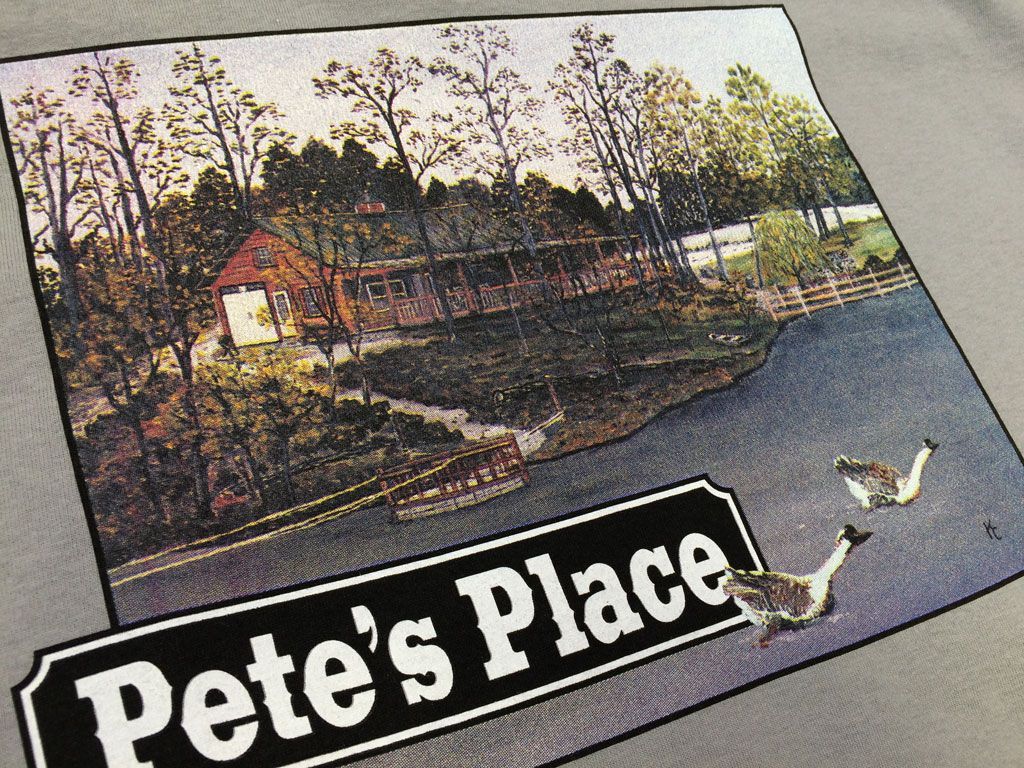 A graphic on a grey background shows a red building by a pond with two geese and a sign reading 