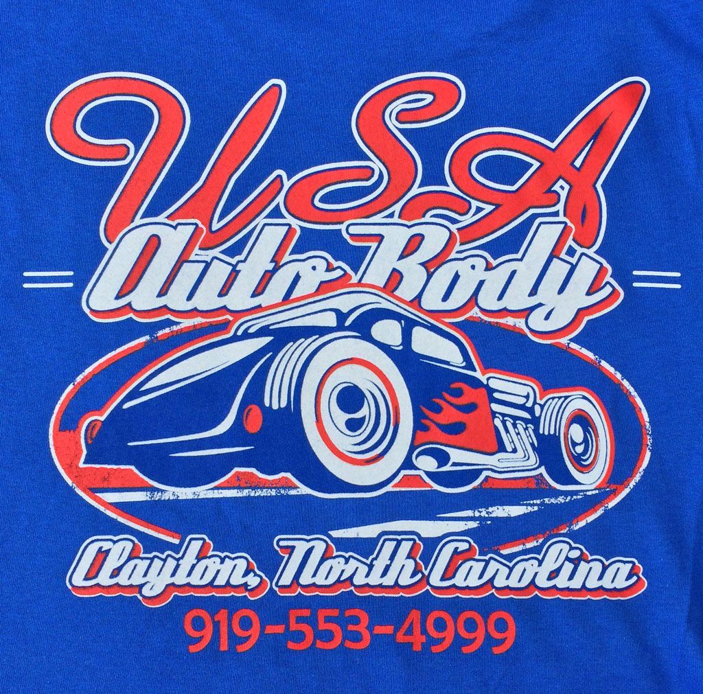 Blue t-shirt graphic for U.S.A. Auto Body in Clayton, NC, featuring a red and white hot rod design and phone number.