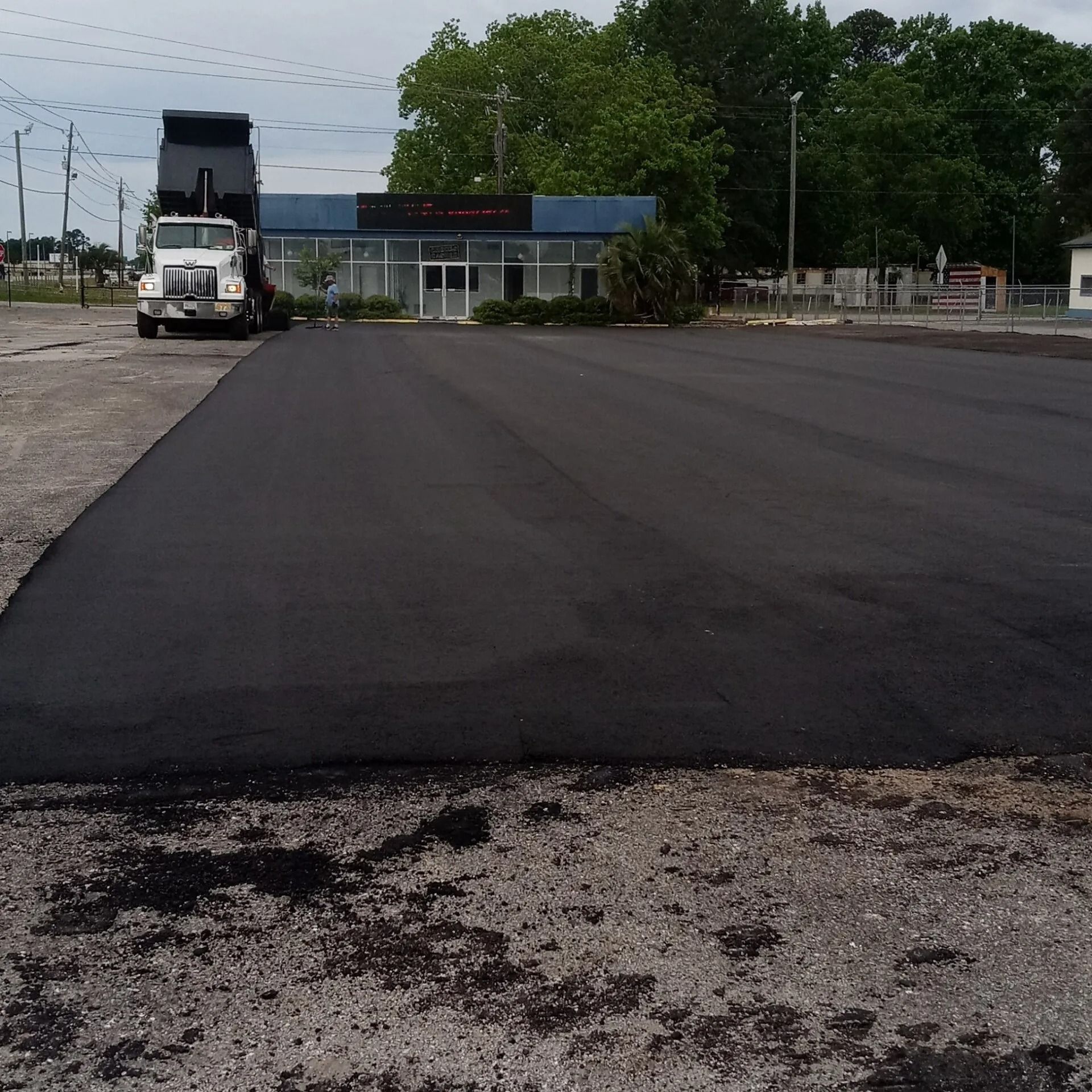 Fresh blacktop paving on a wide road with a truck in the distance at a worksite