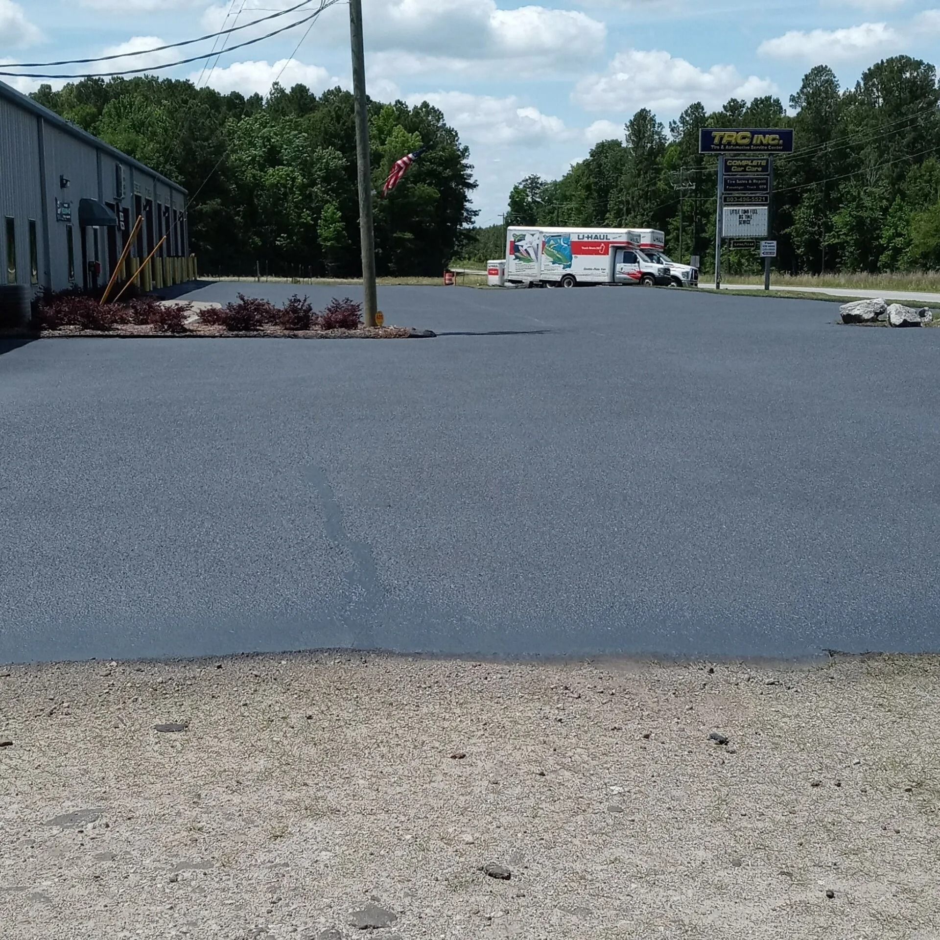 Empty parking lot with a white truck in the distance and a sign by the roadside.
