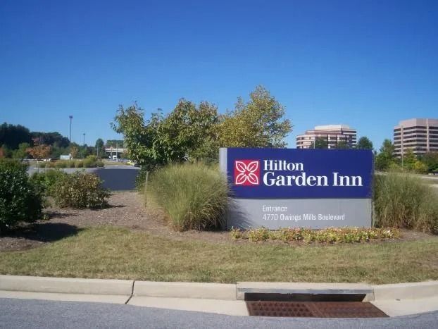 Hilton Garden Inn roadside sign with landscaping under a clear blue sky