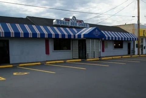 Small storefront with blue-and-white striped awning and parking lot in front