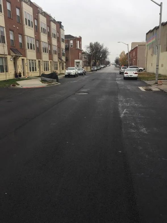Quiet residential street with parked cars and row houses on an overcast day