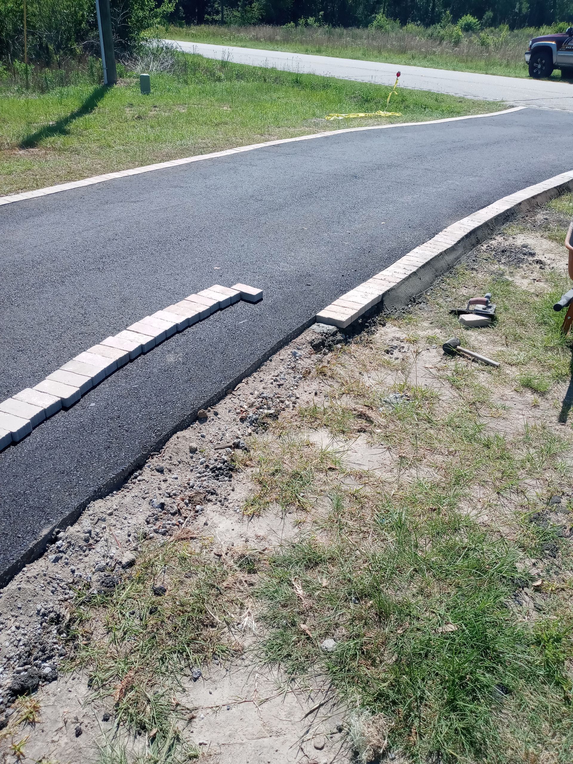 Damaged rural road with a broken asphalt edge and a grassy shoulder beside it