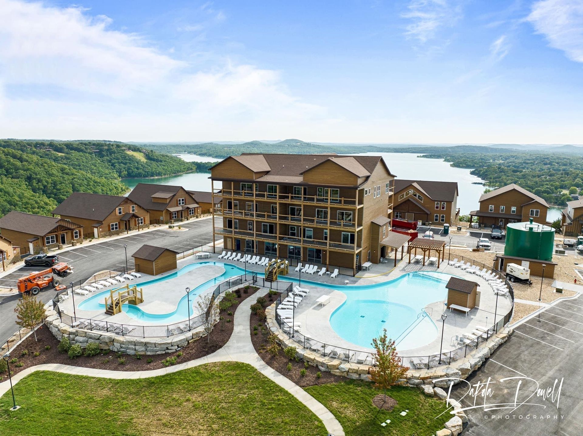 Resort pool complex with slides and multi-story lodge overlooking a river valley