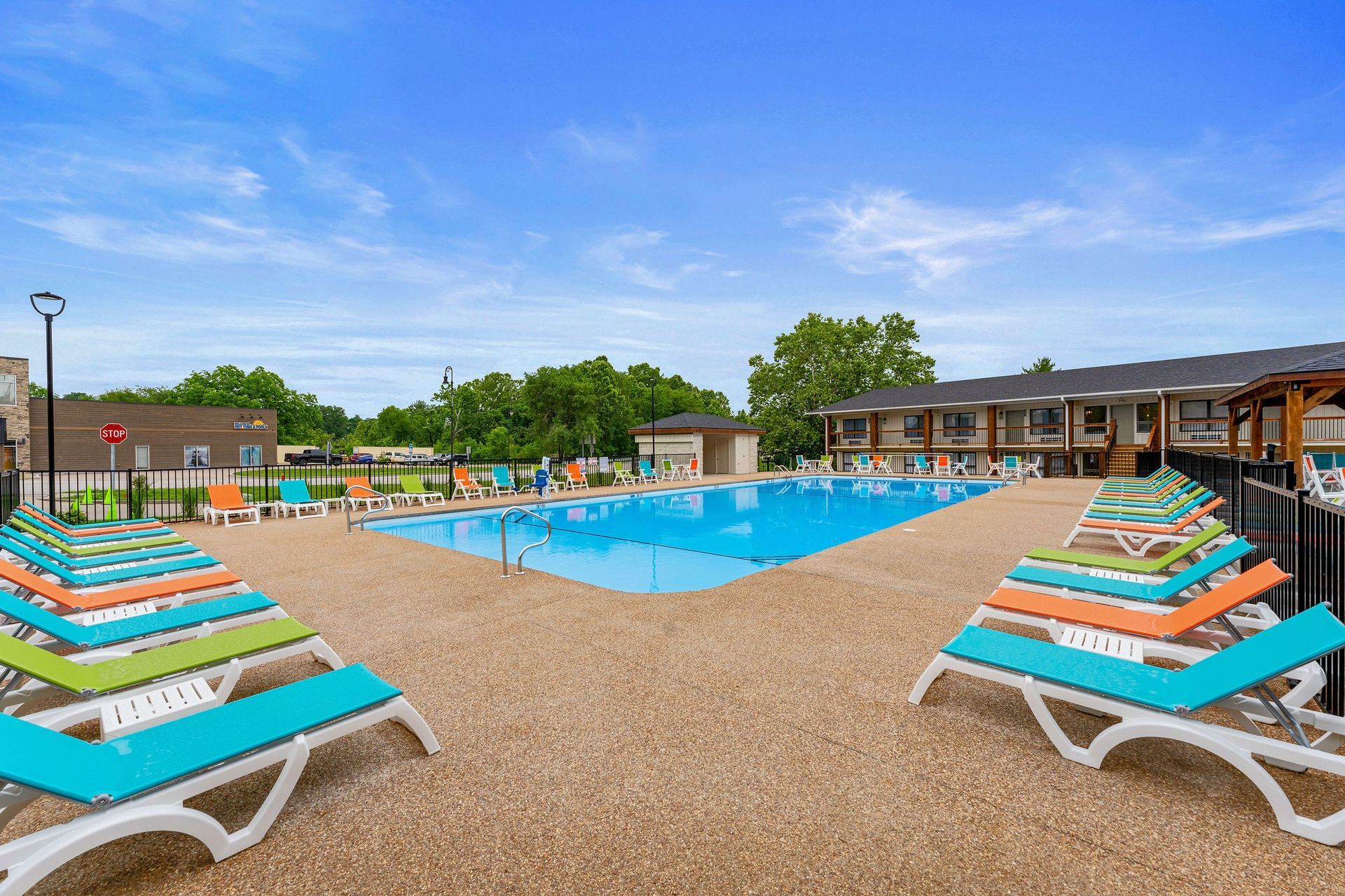 Outdoor resort pool with colorful lounge chairs and a blue sky