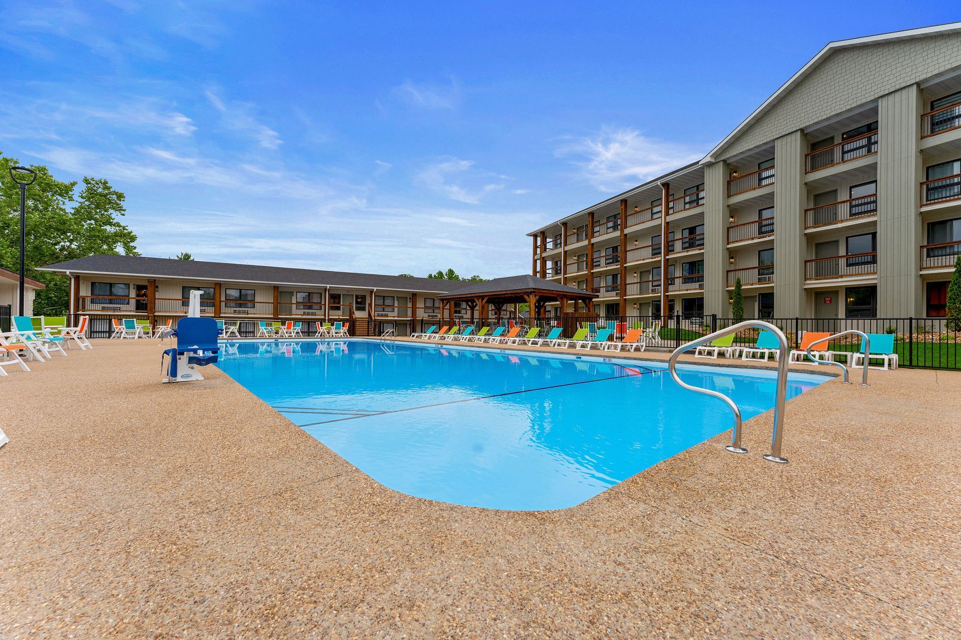 Resort pool with blue water, lounge chairs, and multi-story hotel buildings under a clear sky
