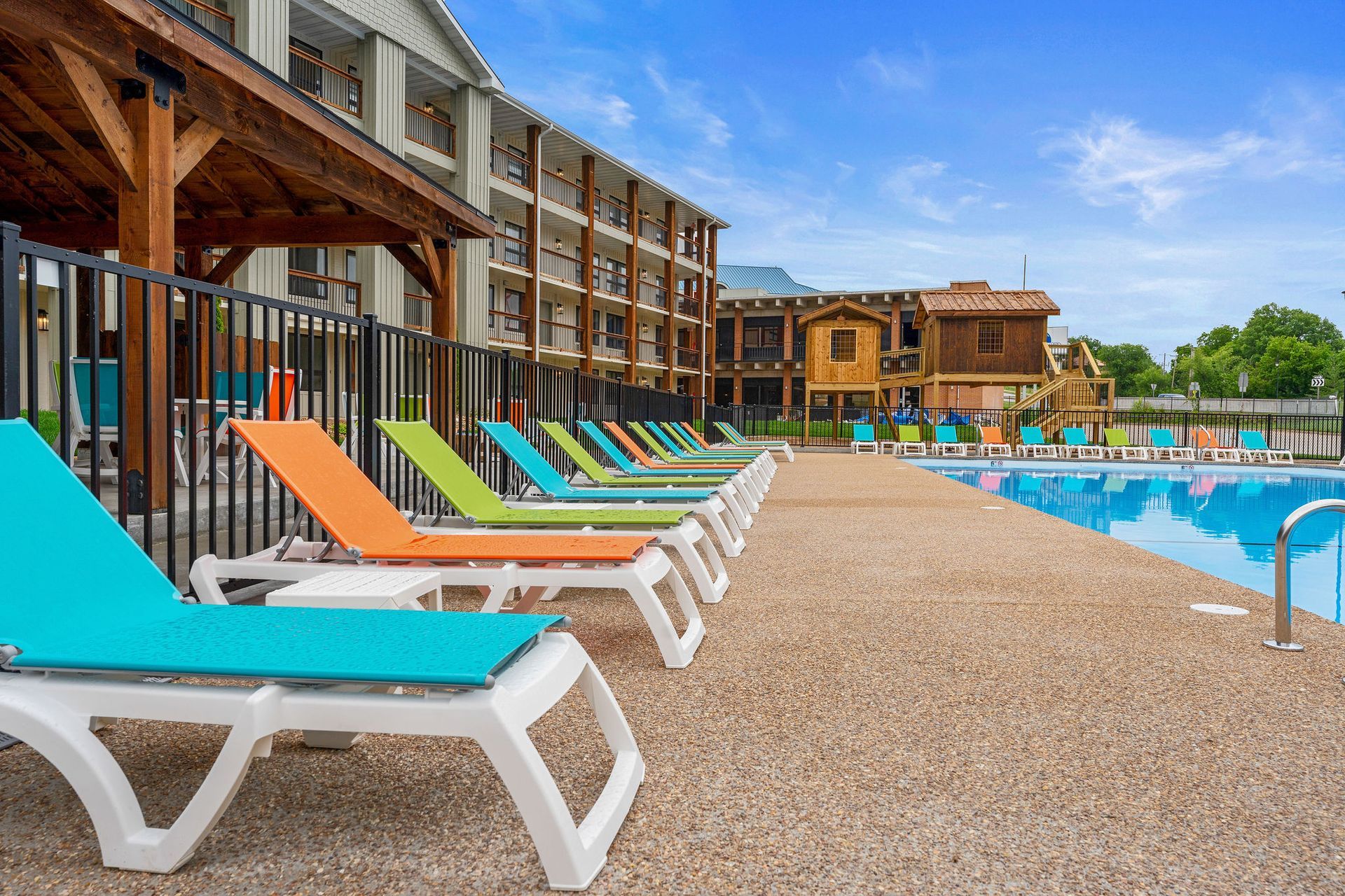 Rows of colorful lounge chairs beside a resort pool under a bright blue sky
