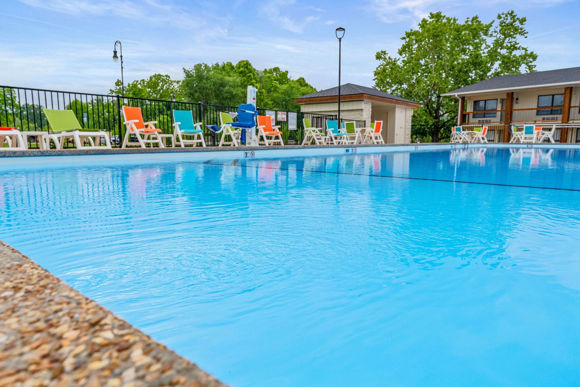 Outdoor swimming pool with blue water, lounge chairs, and a resort building in the background