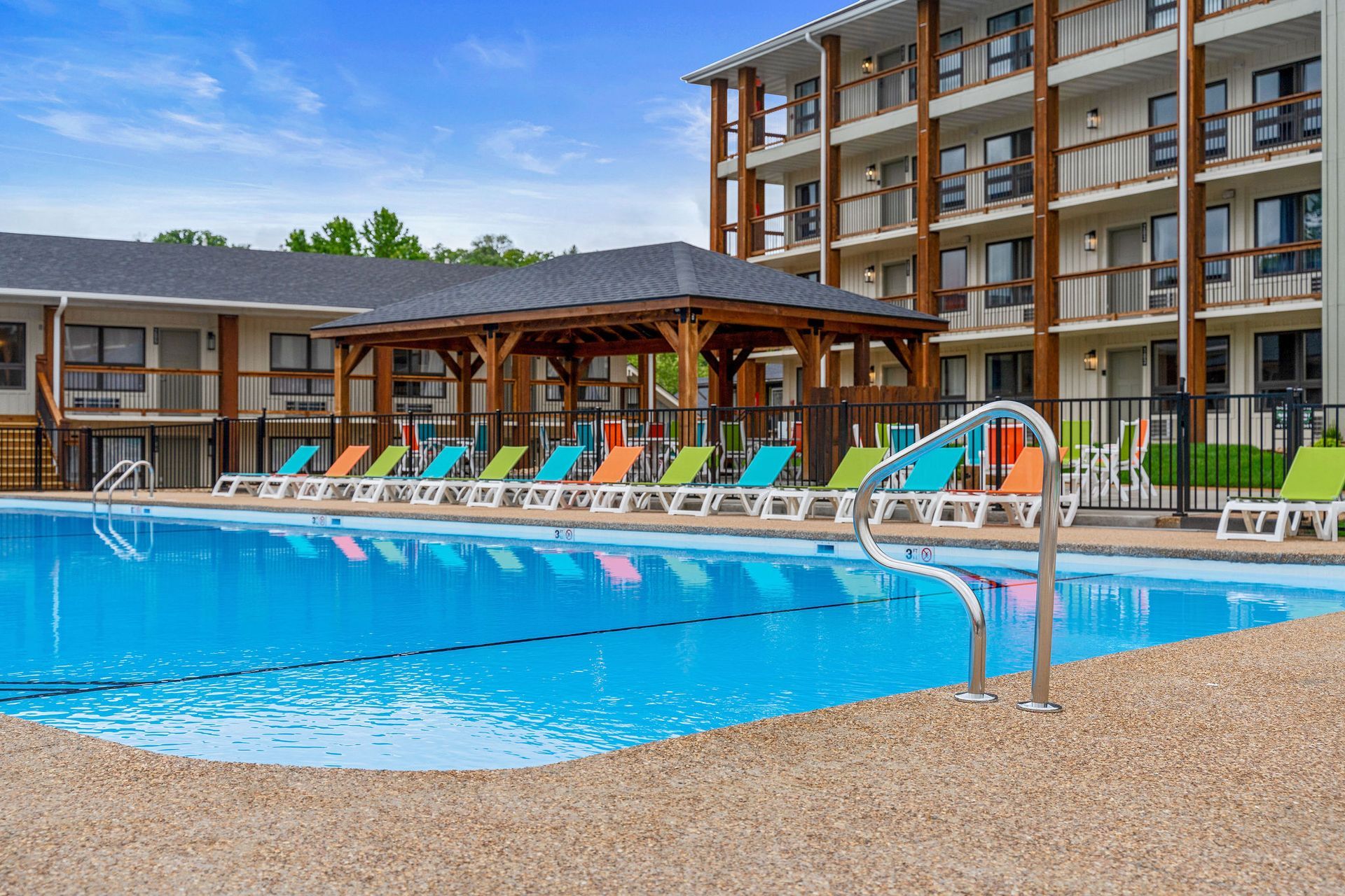 Outdoor hotel pool with lounge chairs, umbrellas, and apartment-style buildings in the background