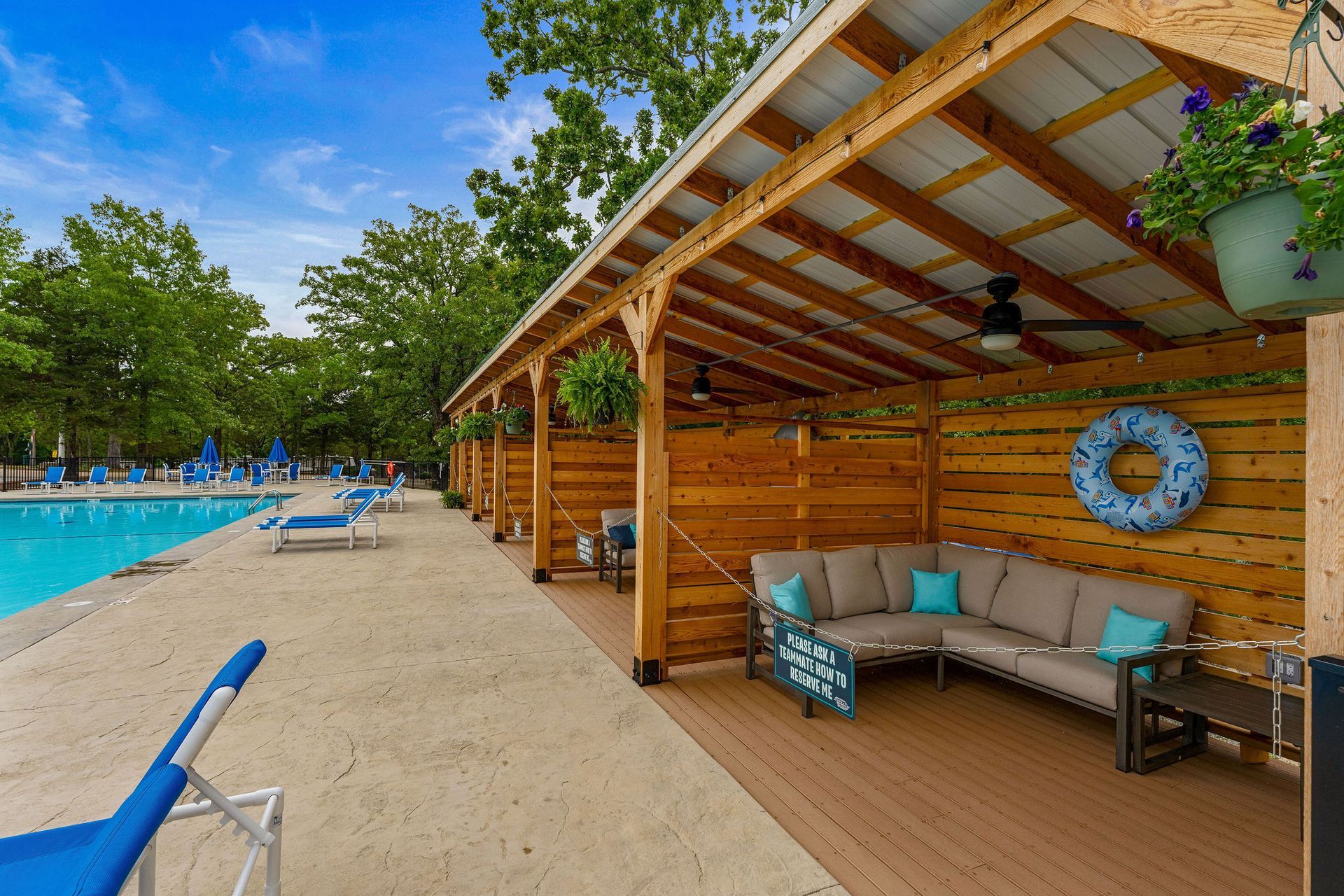 Beachside cabana with couch and turquoise accents beside a resort pool and sandy shore
