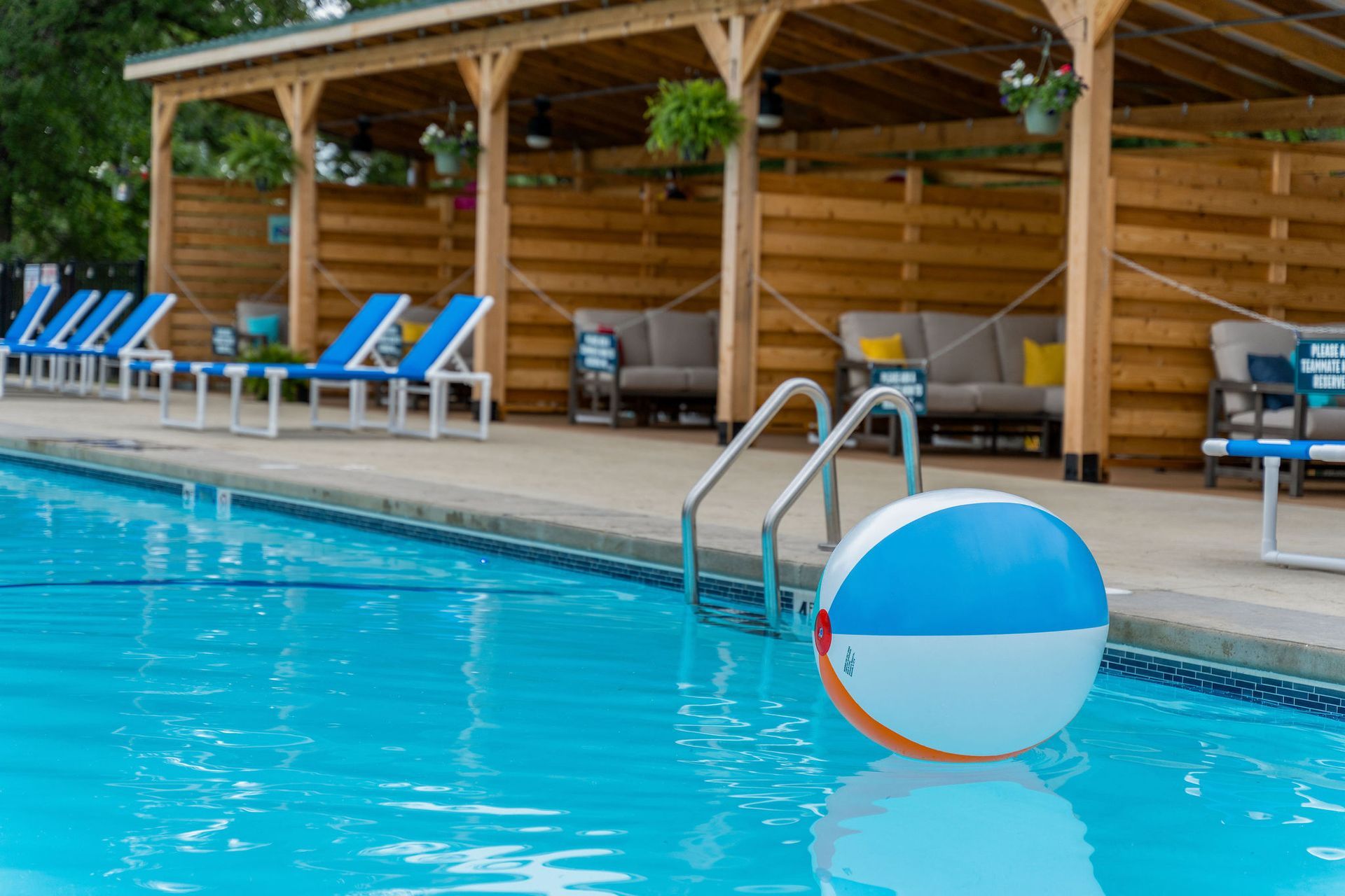 Swimming pool with blue-and-white float, lounge chairs, and a wooden cabana