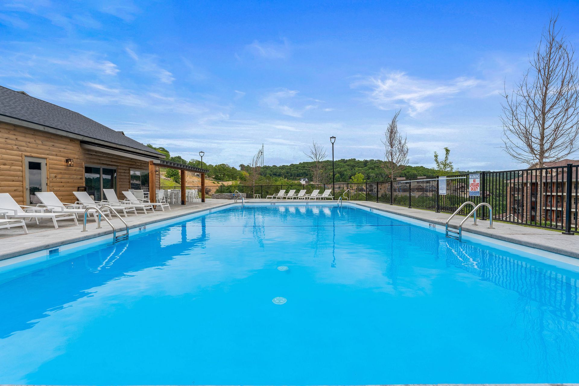 Outdoor swimming pool with bright blue water, lounge chairs, and a modern building under a clear sky