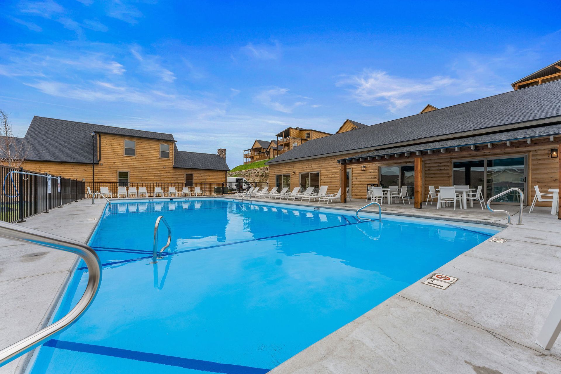 Outdoor swimming pool beside stone buildings under a bright blue sky
