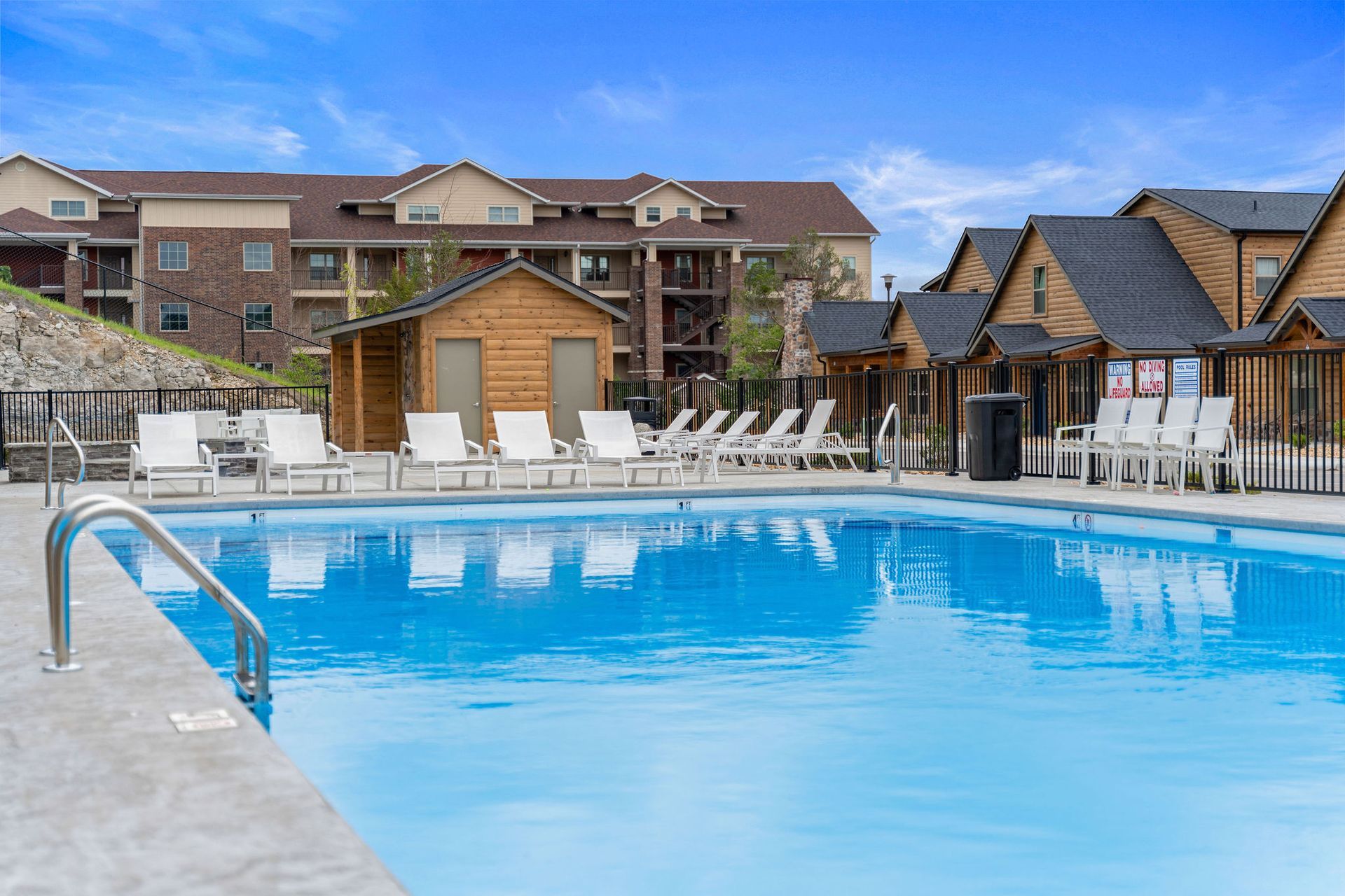 Outdoor pool with lounge chairs and cabanas beside a brick hotel building