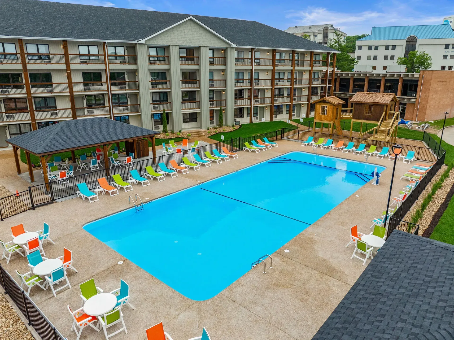 Resort pool courtyard with blue water, lounge chairs, palm trees, and surrounding balconies.