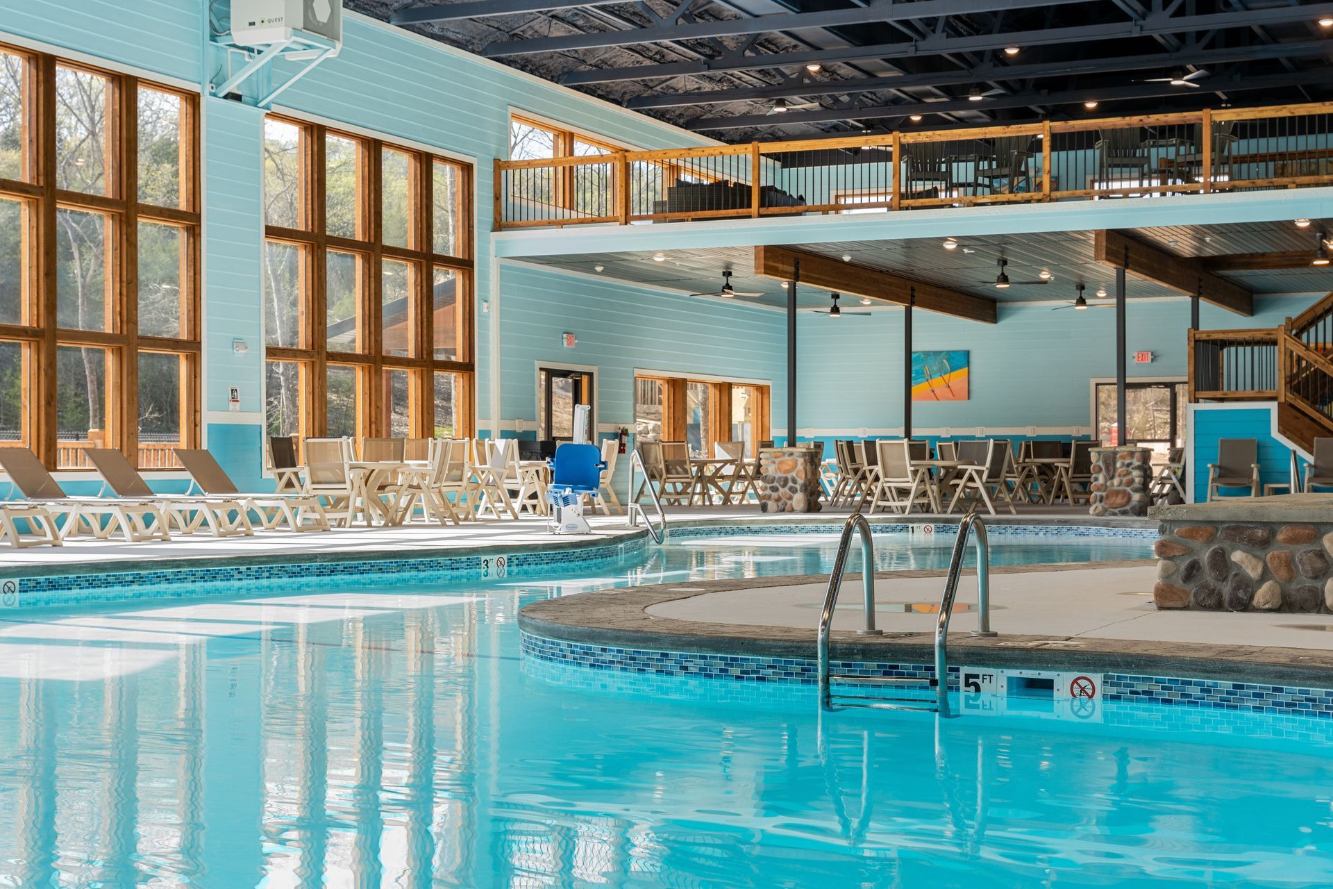 Indoor swimming pool with turquoise water, lounge chairs, and large windows in a bright resort setting