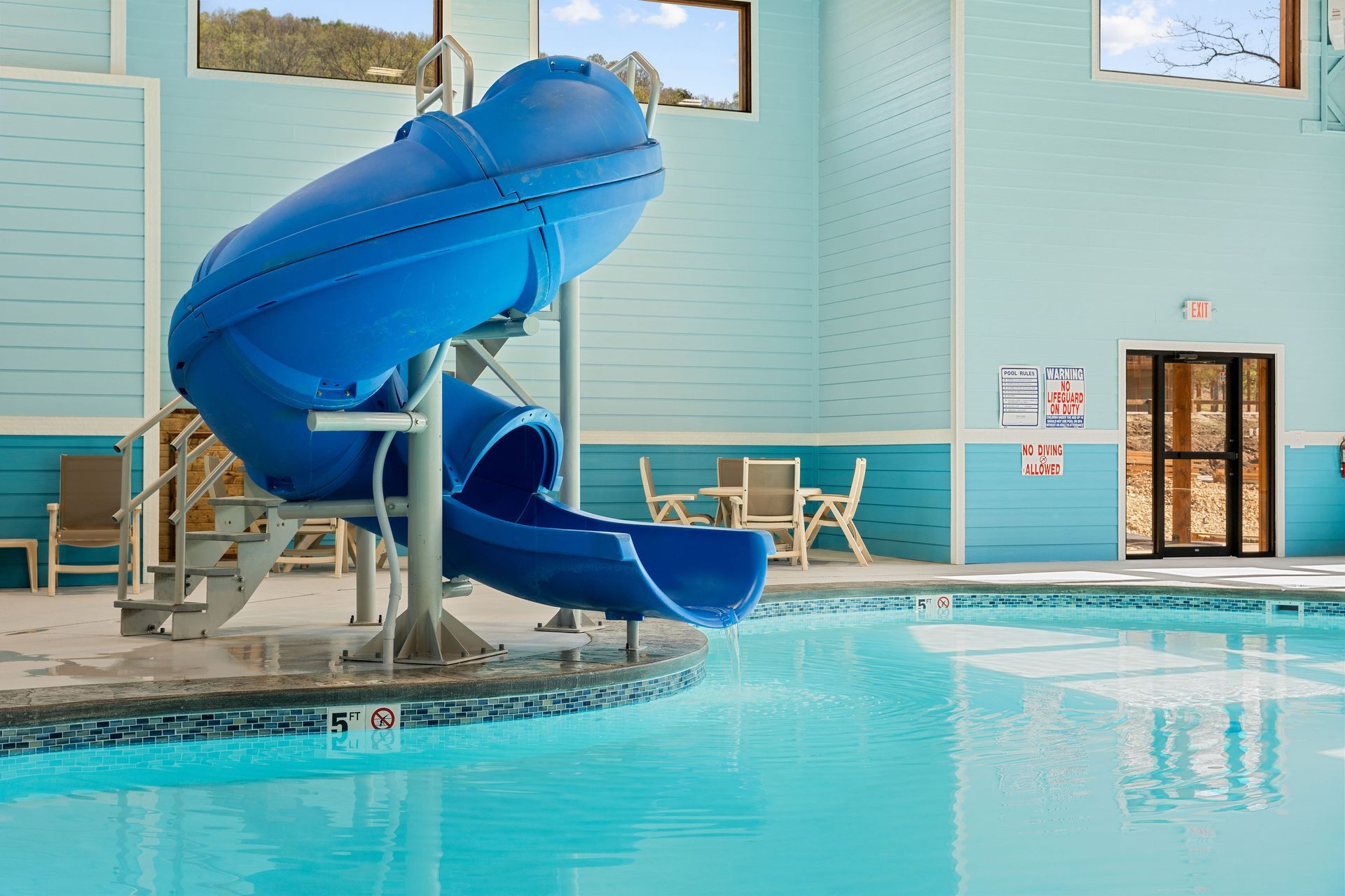 Indoor pool with a blue water slide and lifeguard chairs beside the water