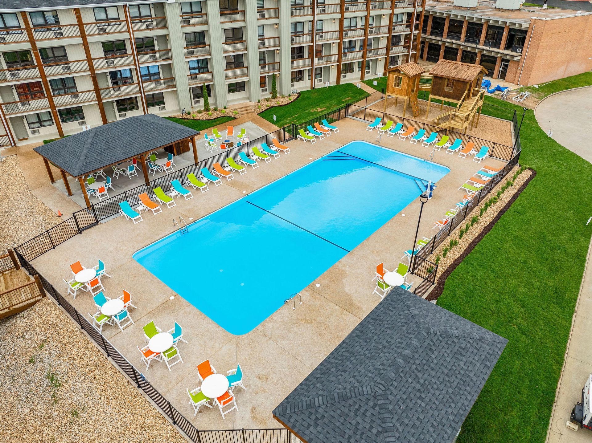 Outdoor pool courtyard with blue pool, colorful loungers, umbrellas, and apartment balconies around it