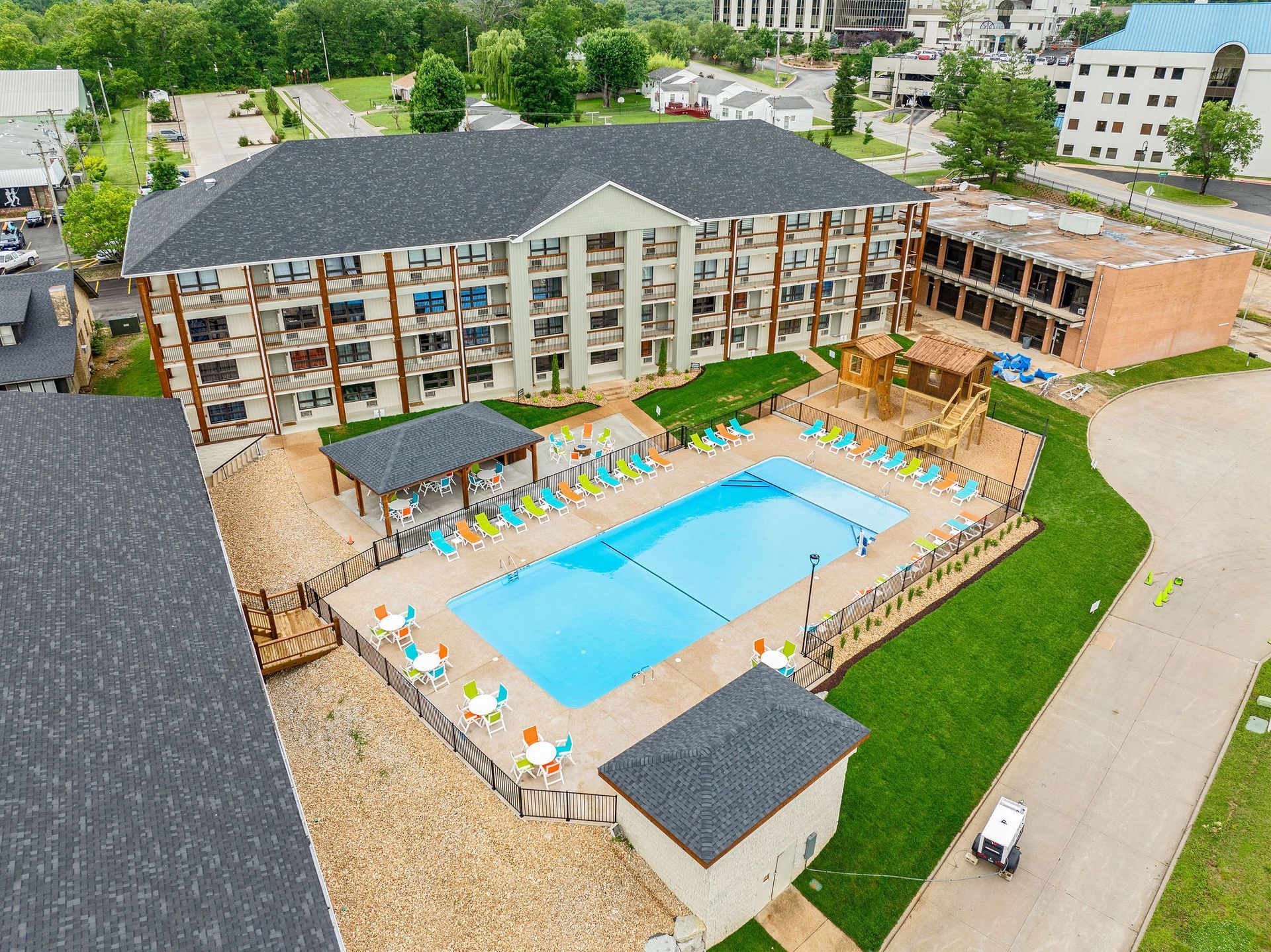 Aerial view of a hotel courtyard with a large swimming pool and lounge chairs surrounded by buildings.