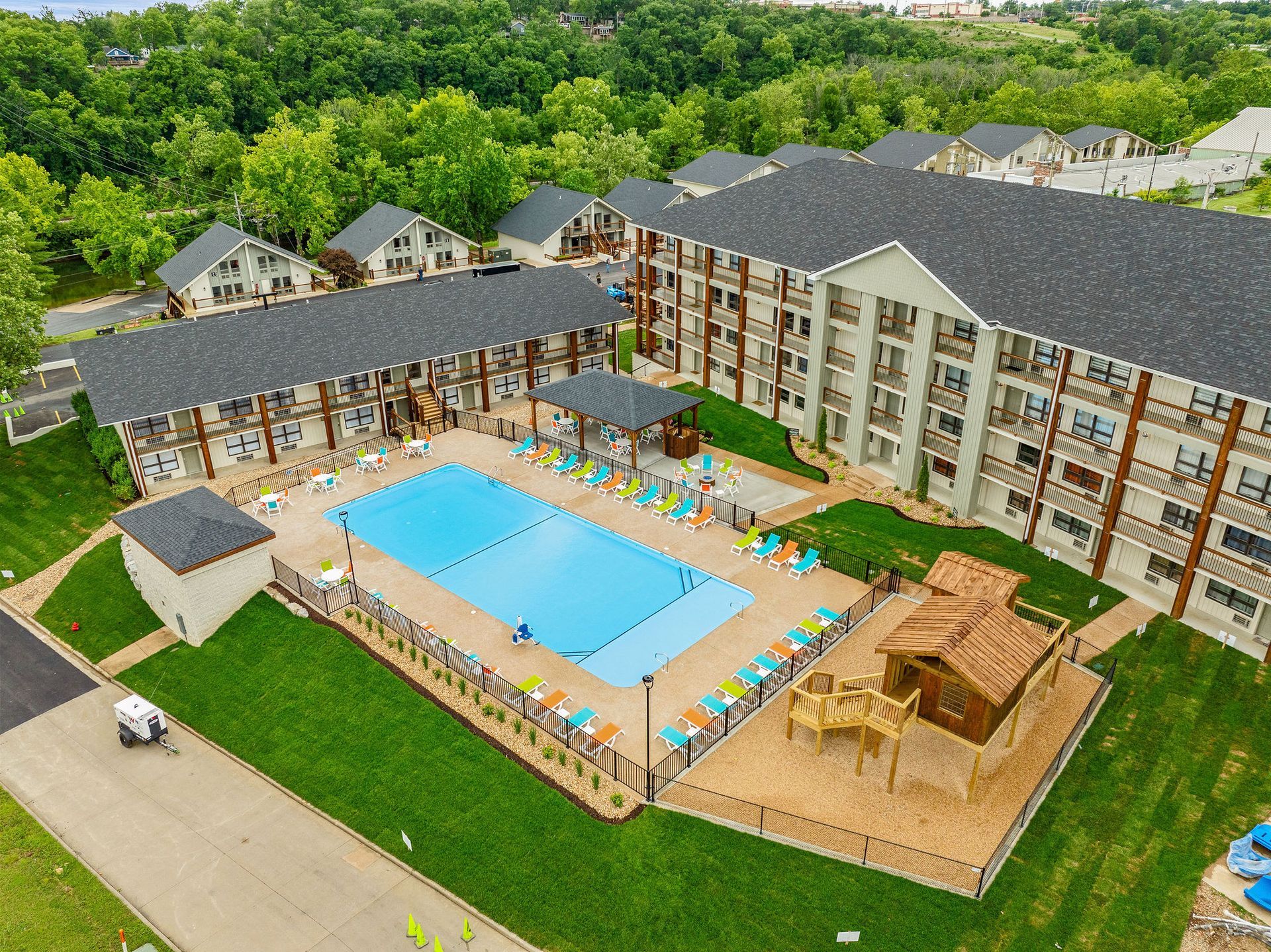 Aerial view of a resort pool courtyard with lounge chairs, cabanas, and surrounding hotel buildings.