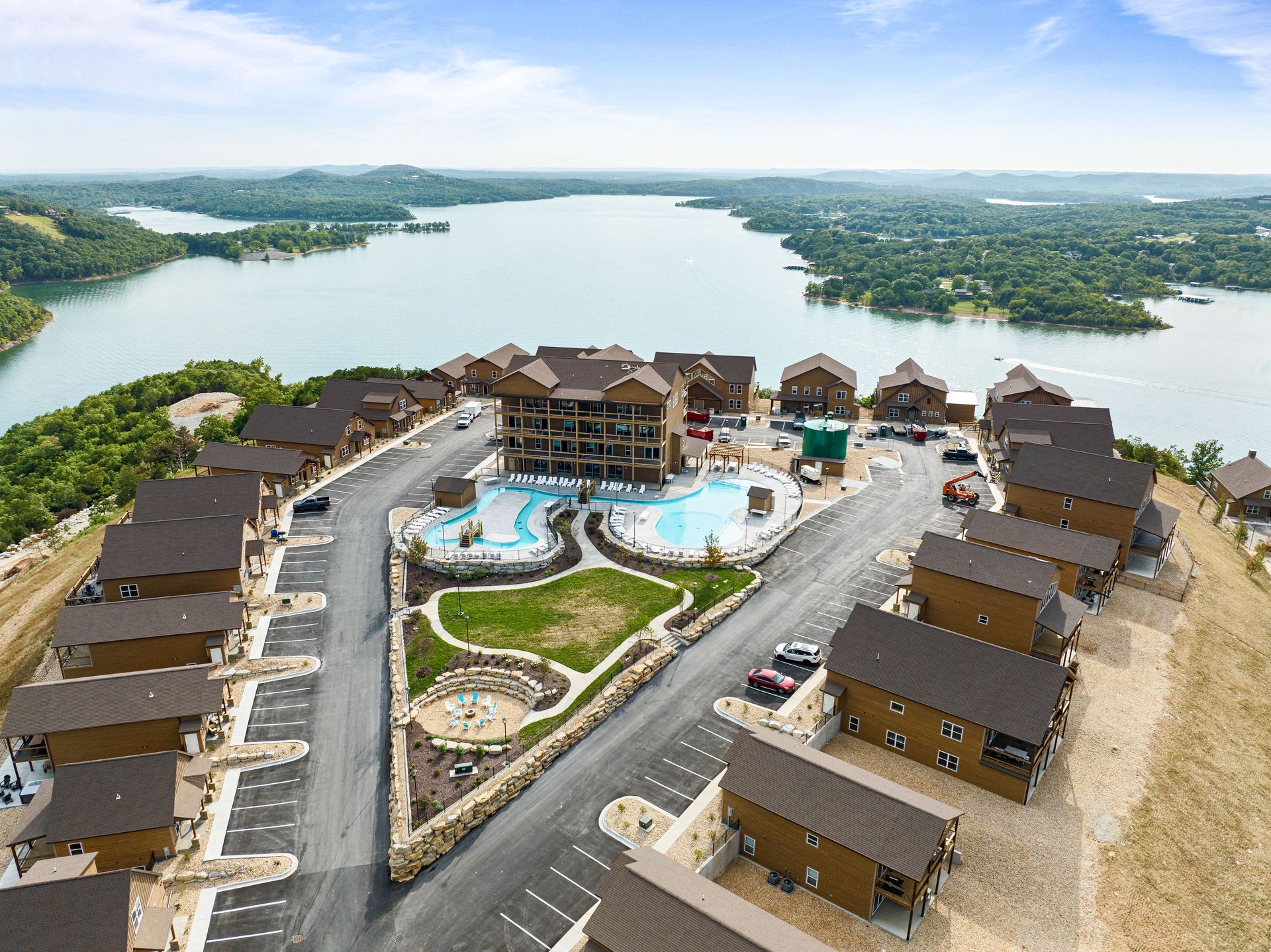 Aerial view of a lakeside resort with pools, villas, and a large lake in the background