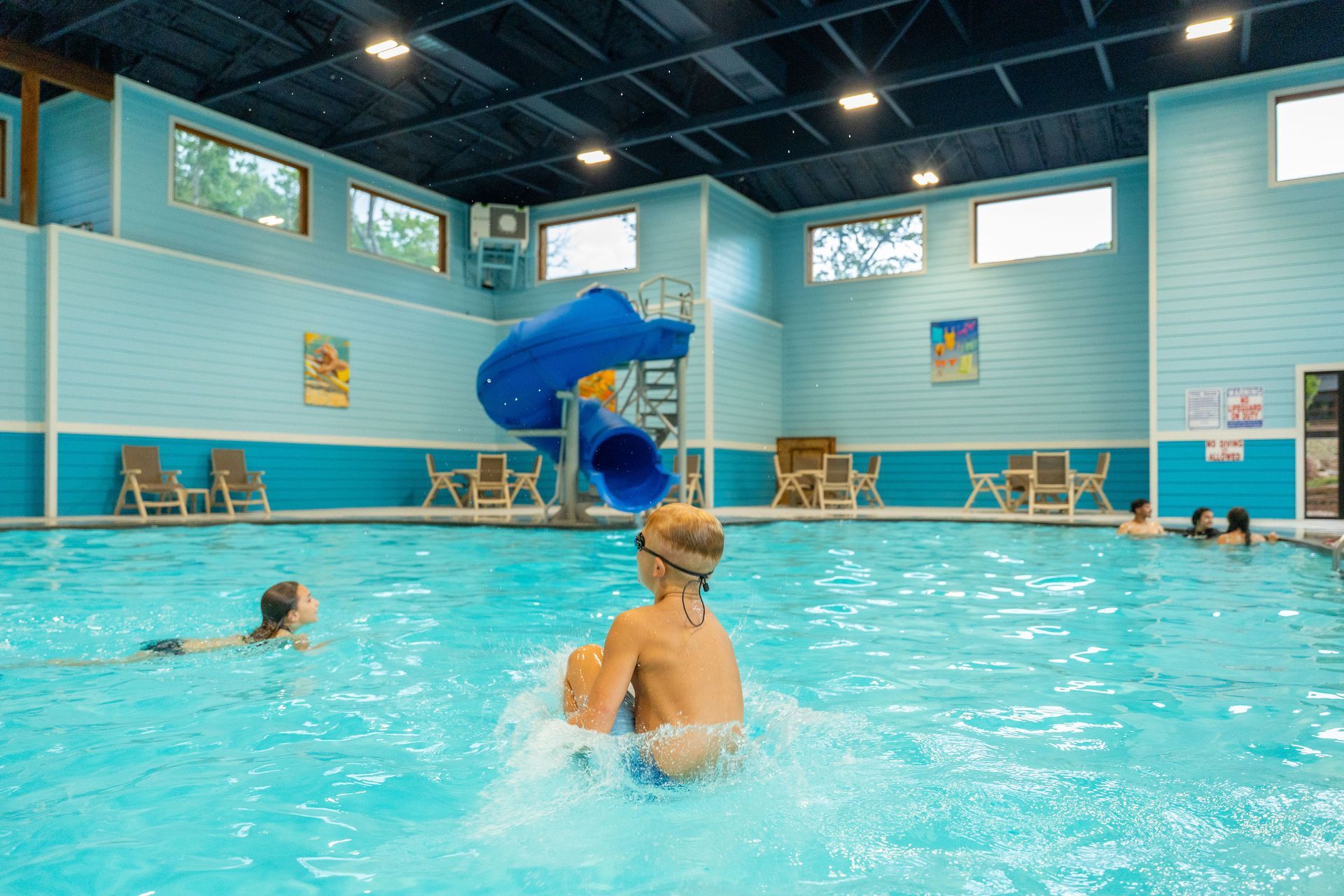 Indoor swimming pool with a blue slide and several swimmers in clear water