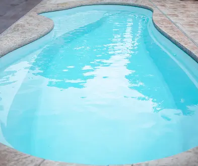 Curved outdoor swimming pool with clear turquoise water and stone deck edging
