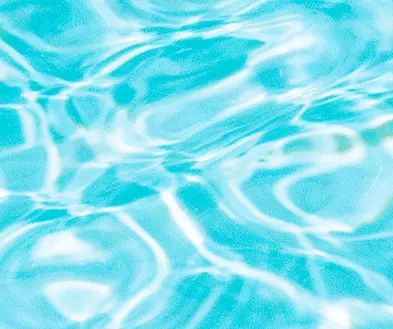 Light blue swimming pool water with rippling reflections of sunlight