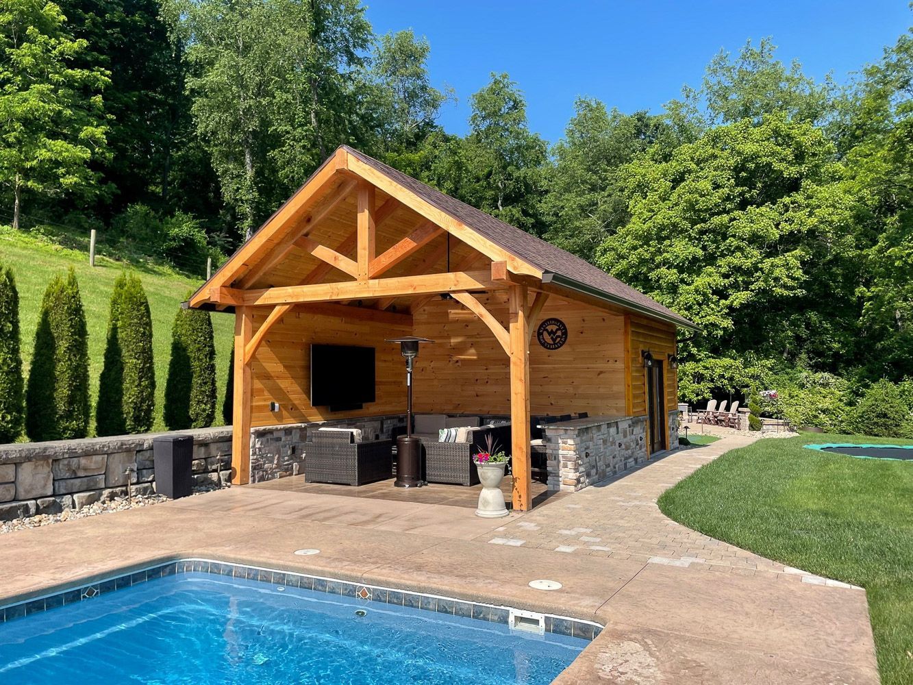 A wooden pavilion with a swimming pool in front of it.