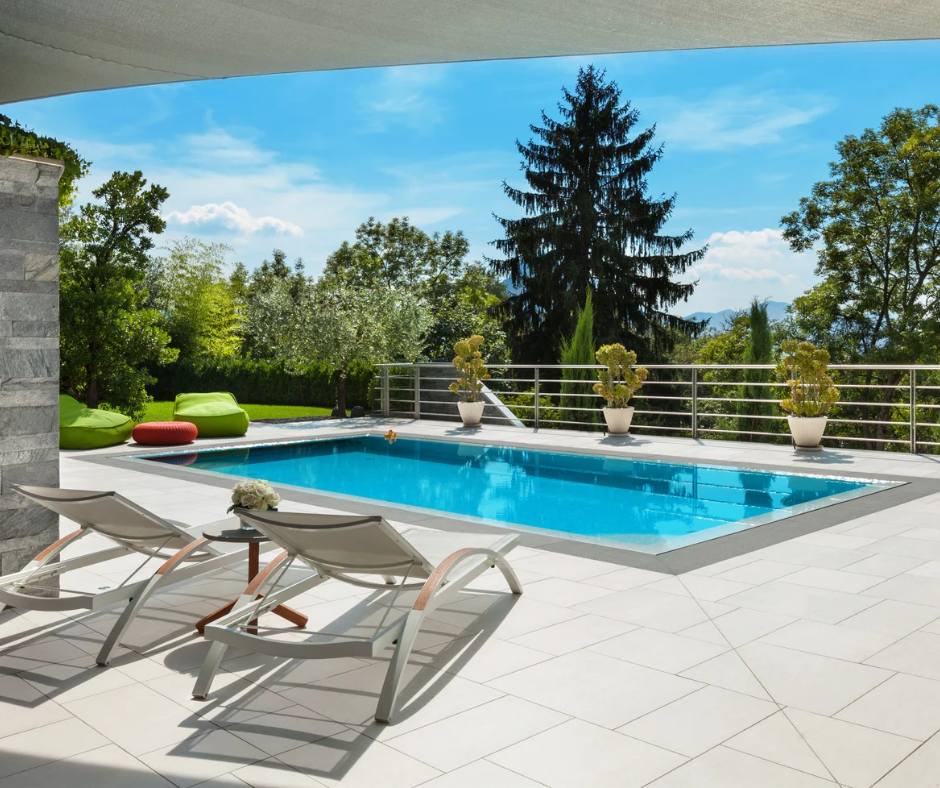 A large swimming pool is surrounded by chairs and trees